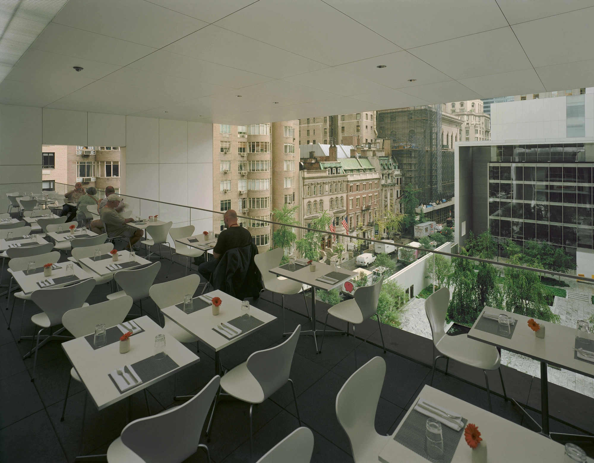 Museum of Modern Art in New York by Yoshio Taniguchi — An elevated dining space within MoMA's Taniguchi expansion, captured from an interior vantage point overlooking a verdant courtyard.