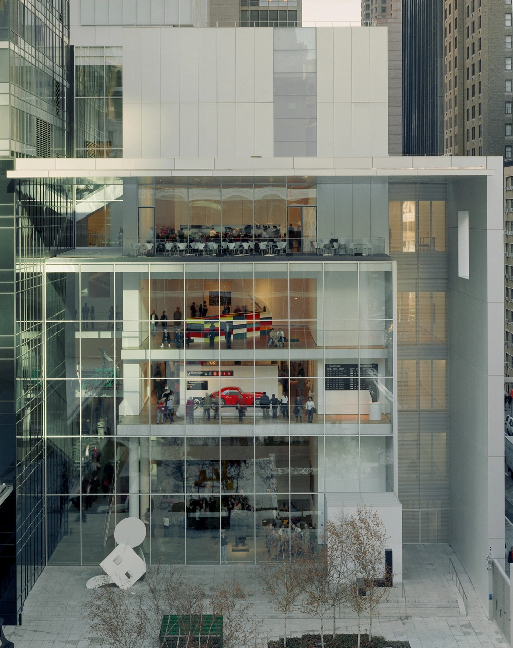 Museum of Modern Art in New York by Yoshio Taniguchi — This street-level perspective captures MoMA's 2004 expansion with its defining characteristic: a transparent ground floor that dissolves the boundary...