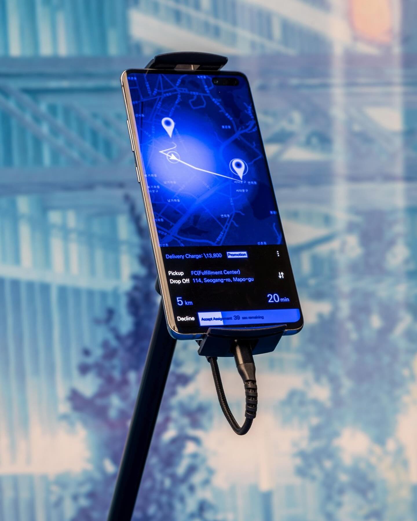 Many Worlds Over by Ayoung Kim at Hamburger Bahnhof — A smartphone mounted on a black stand displays a navigation application with a cobalt-blue interface.