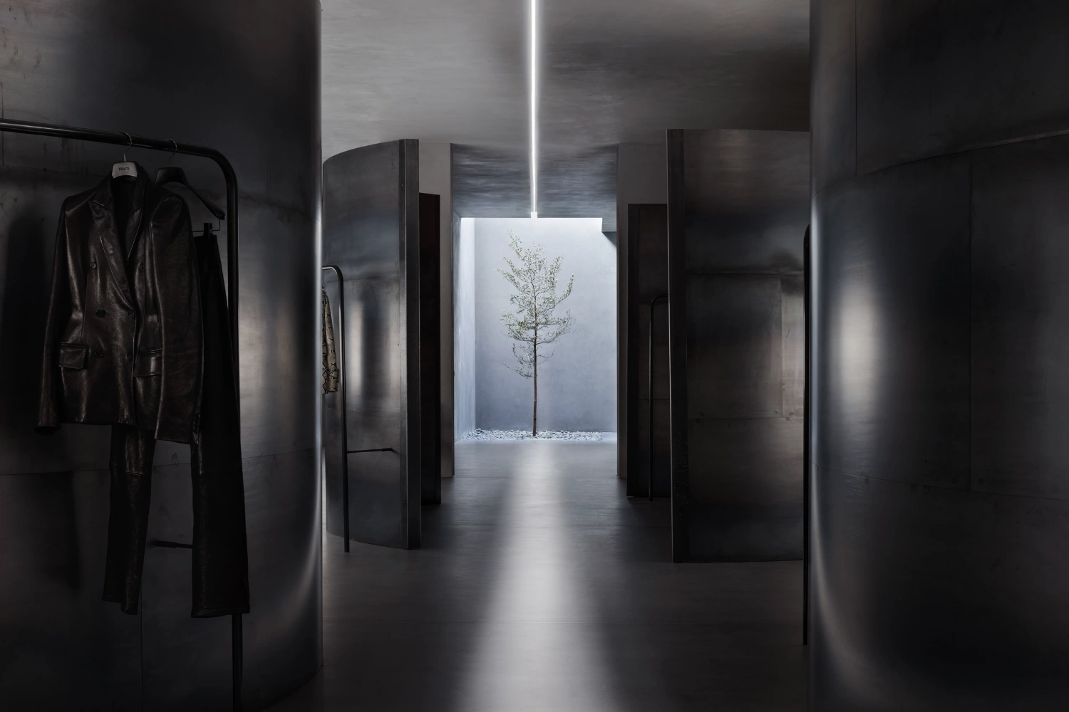 KHAITE Flagship Store by Griffin Frazen — A polished concrete corridor with directional surface striations reflects overhead light, creating subtle highlights across the floor plane.