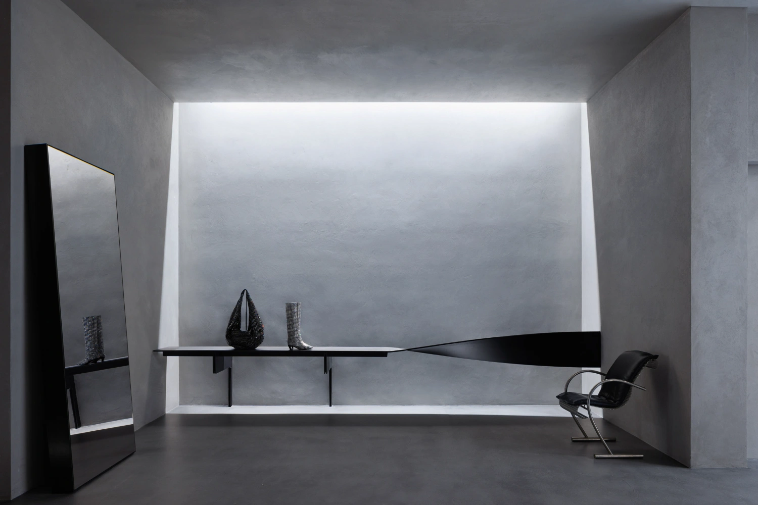 KHAITE Flagship Store by Griffin Frazen — A narrow interior corridor defined by curved dark steel partitions that converge toward a distant chamber.