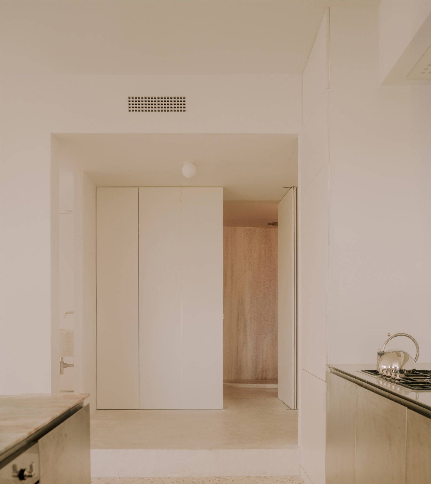 'Astral Weeks' by Oblique — A kitchen-bedroom threshold within a converted 1970s office building, photographed from the cooking zone looking toward the sleeping quarters.
