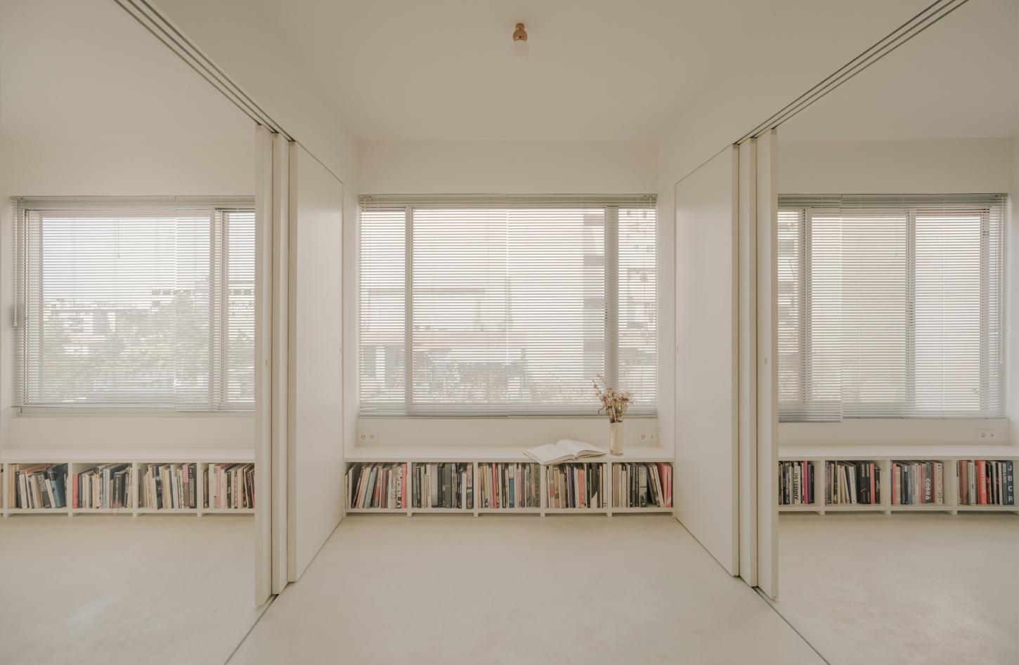 'Astral Weeks' by Oblique — A symmetrical interior view across a divided living space, structured by two load-bearing columns that create a tripartite composition.