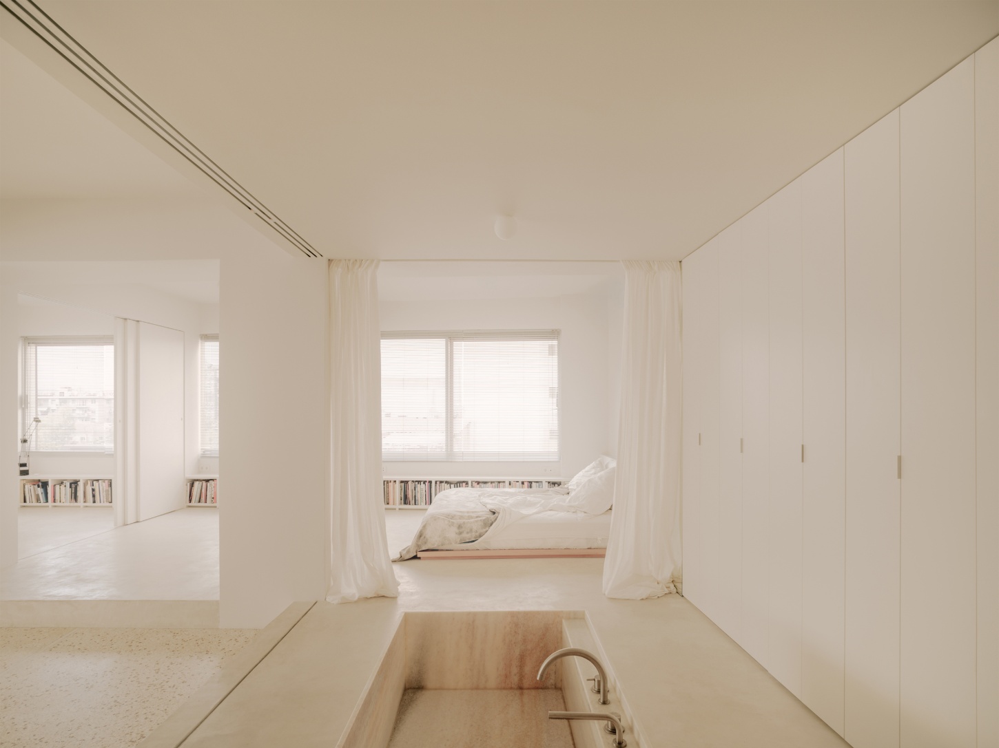 'Astral Weeks' by Oblique — View through the kitchen zone toward the bedroom alcove, framed by the central structural void that divides the apartment.