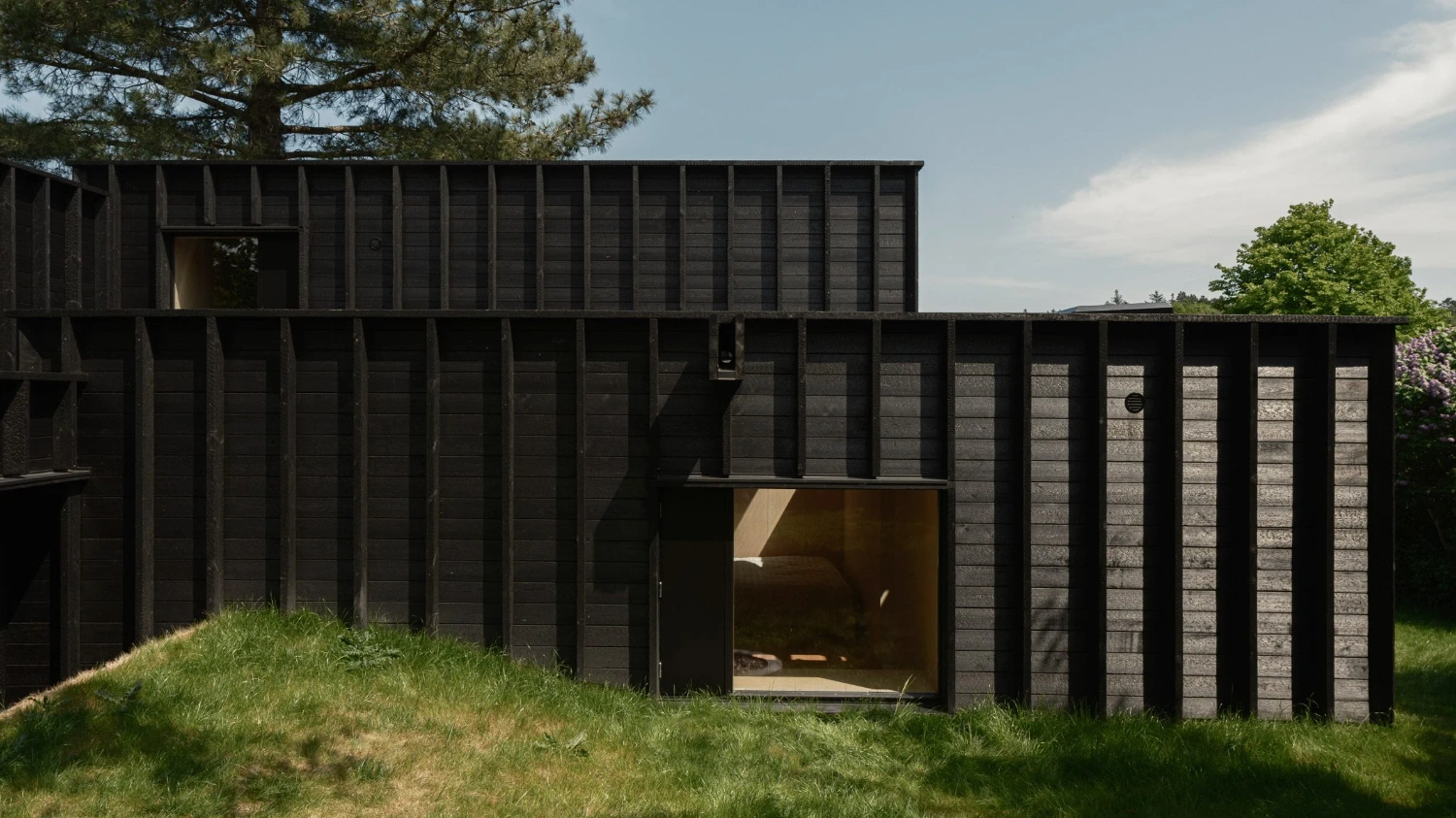 House with a Hidden Atrium by Förstberg Ling — The blackened pine facade presents a gridded composition of vertical timber ribs that cast deep shadow lines across the elevation.