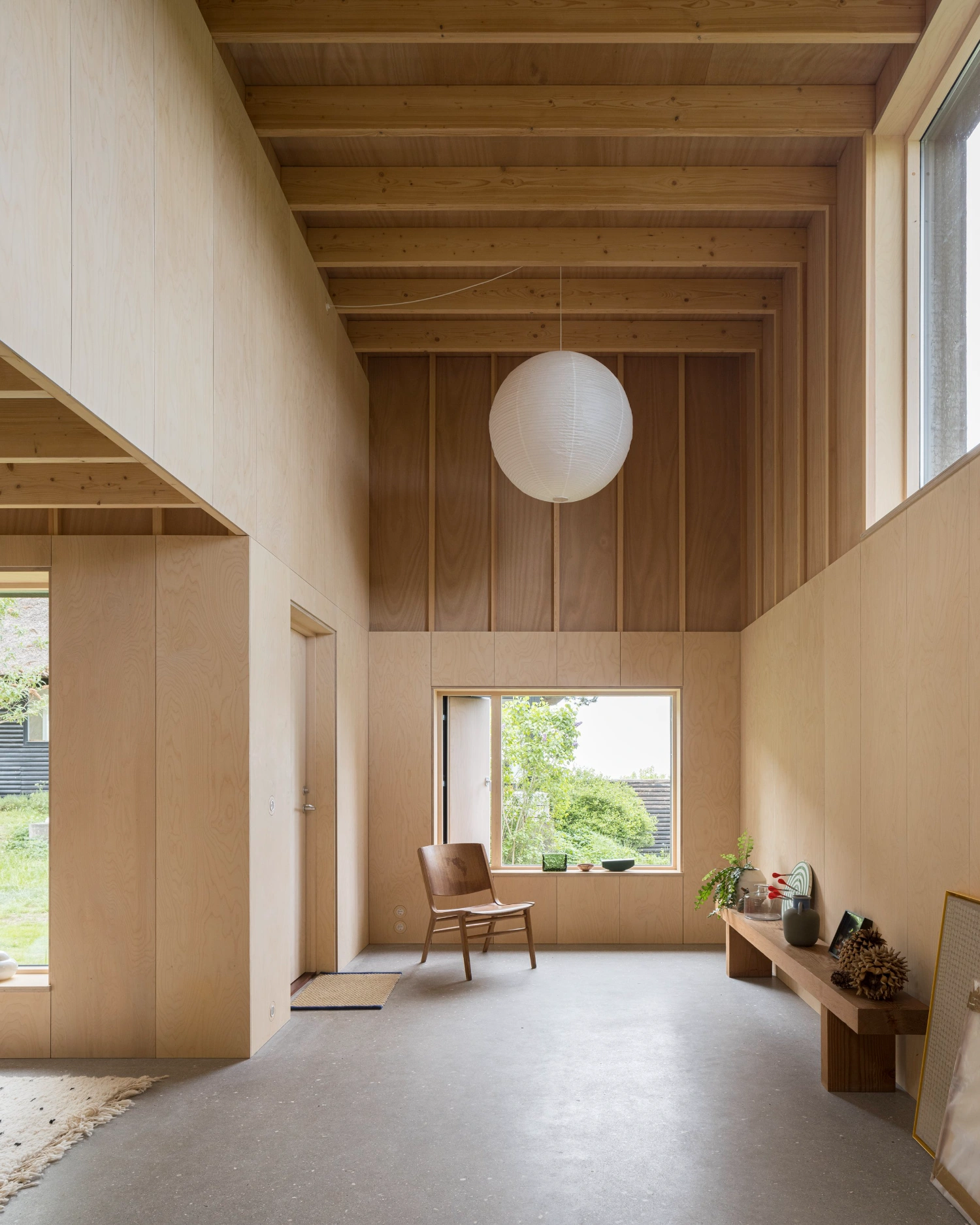 House with a Hidden Atrium by Förstberg Ling — The central atrium volume is revealed through a double-height interior characterized by exposed timber beam ceilings with regular structural intervals.