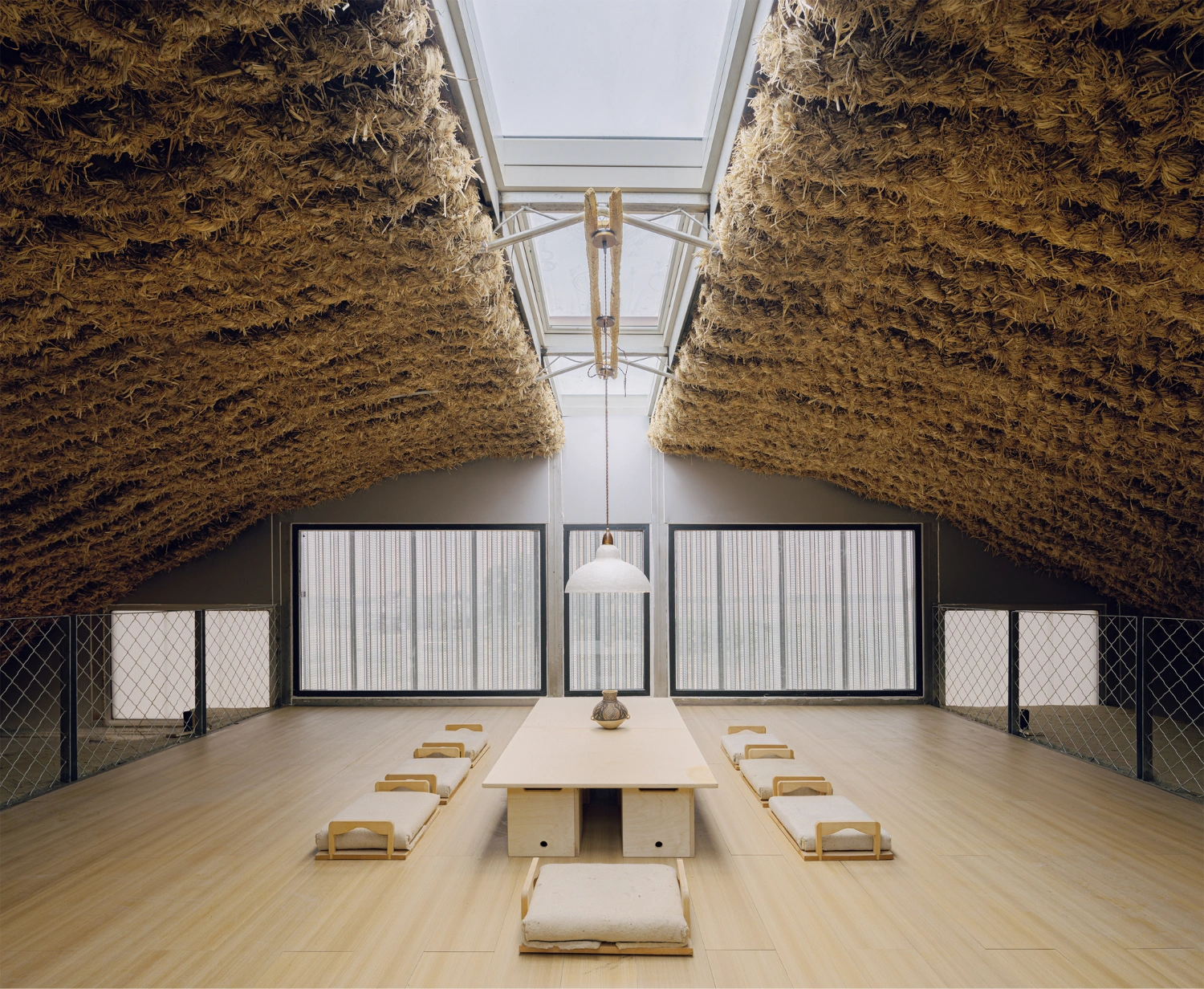 Home in the Badain Jaran Desert by School of Architecture and Urban Planning NJU — A timber-floored interior framed by two monolithic straw-brick walls that rise the full height of the space, creating a narrow canyon-like passage.