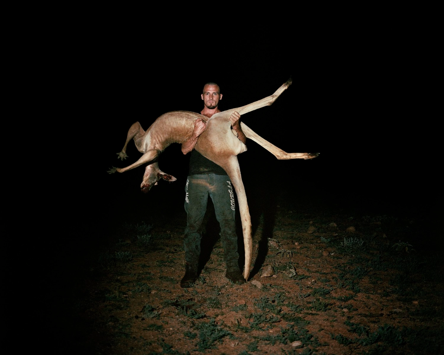 Big Sky by Adam Ferguson — A man holds a large fish horizontally across his body in the Australian outback at dusk, his arms extended in a wide gesture of display.