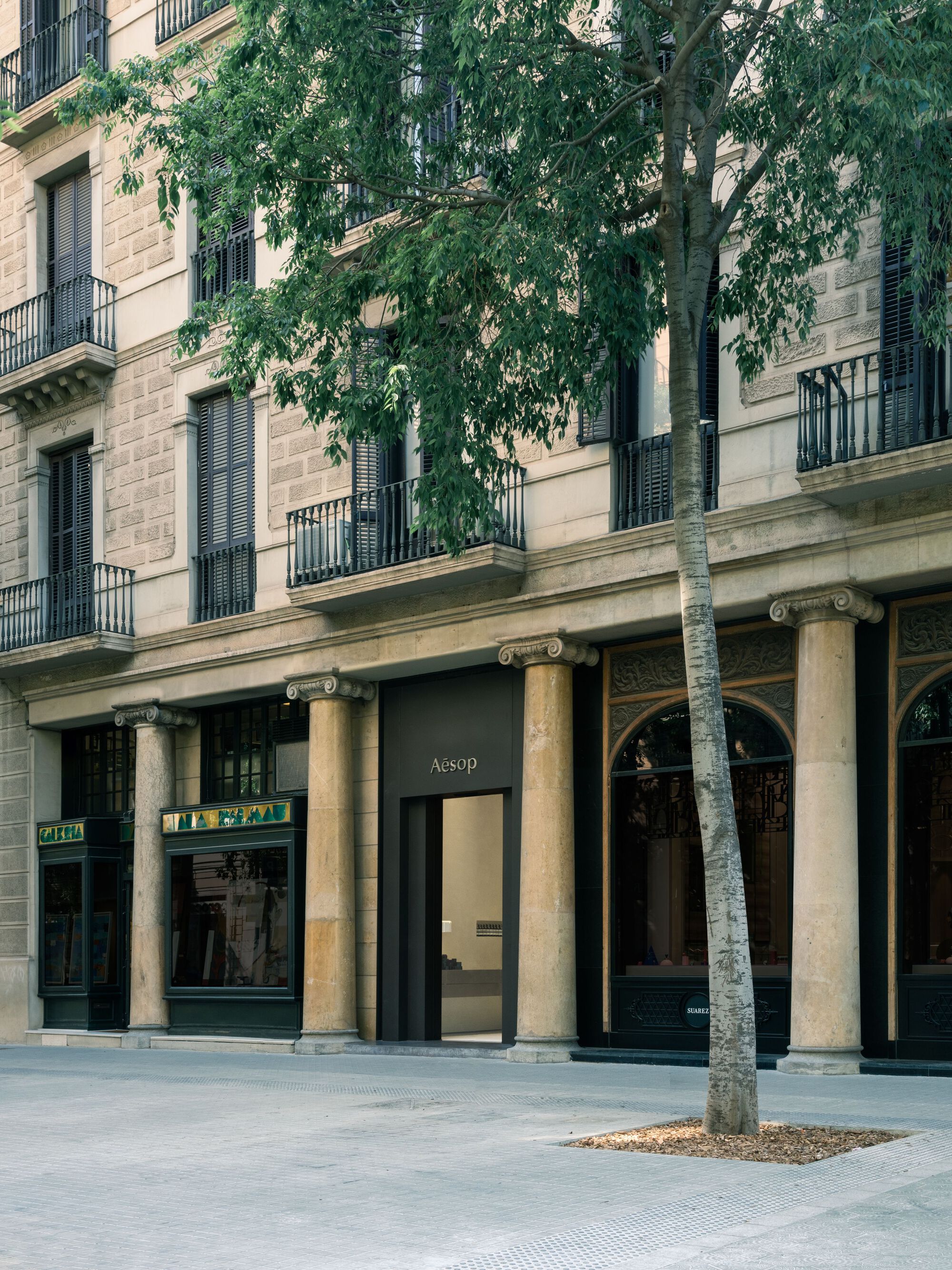 Aesop Store Barcelona by BAROZZI VEIGA — The Aesop storefront anchors the ground plane of a Haussmann-era building in Barcelona's urban grid.