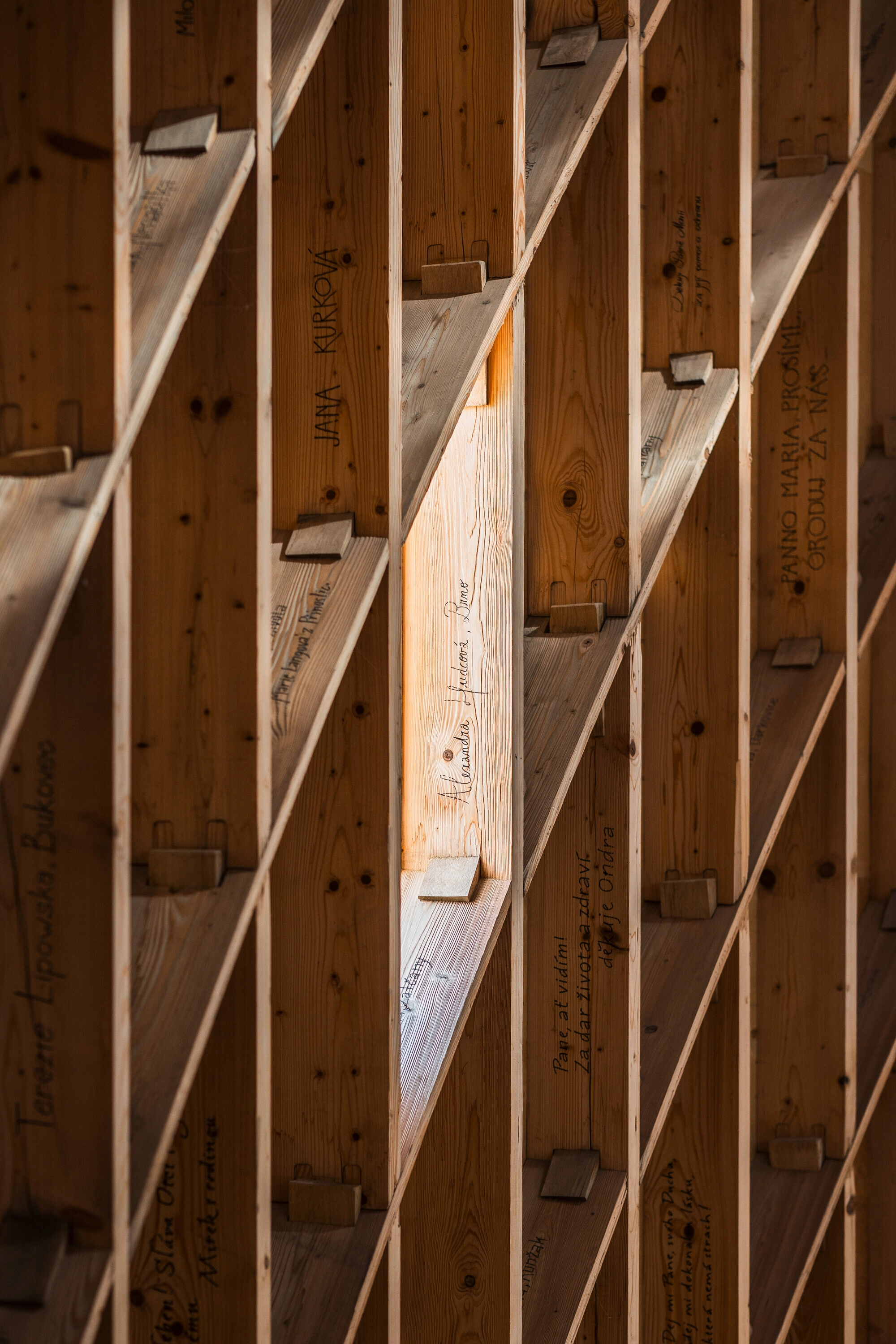 Our Lady of Sorrows Chapel by RCNKSK — A close-up view of the chapel's timber structural framework reveals the post-and-beam construction beneath the roof plane.