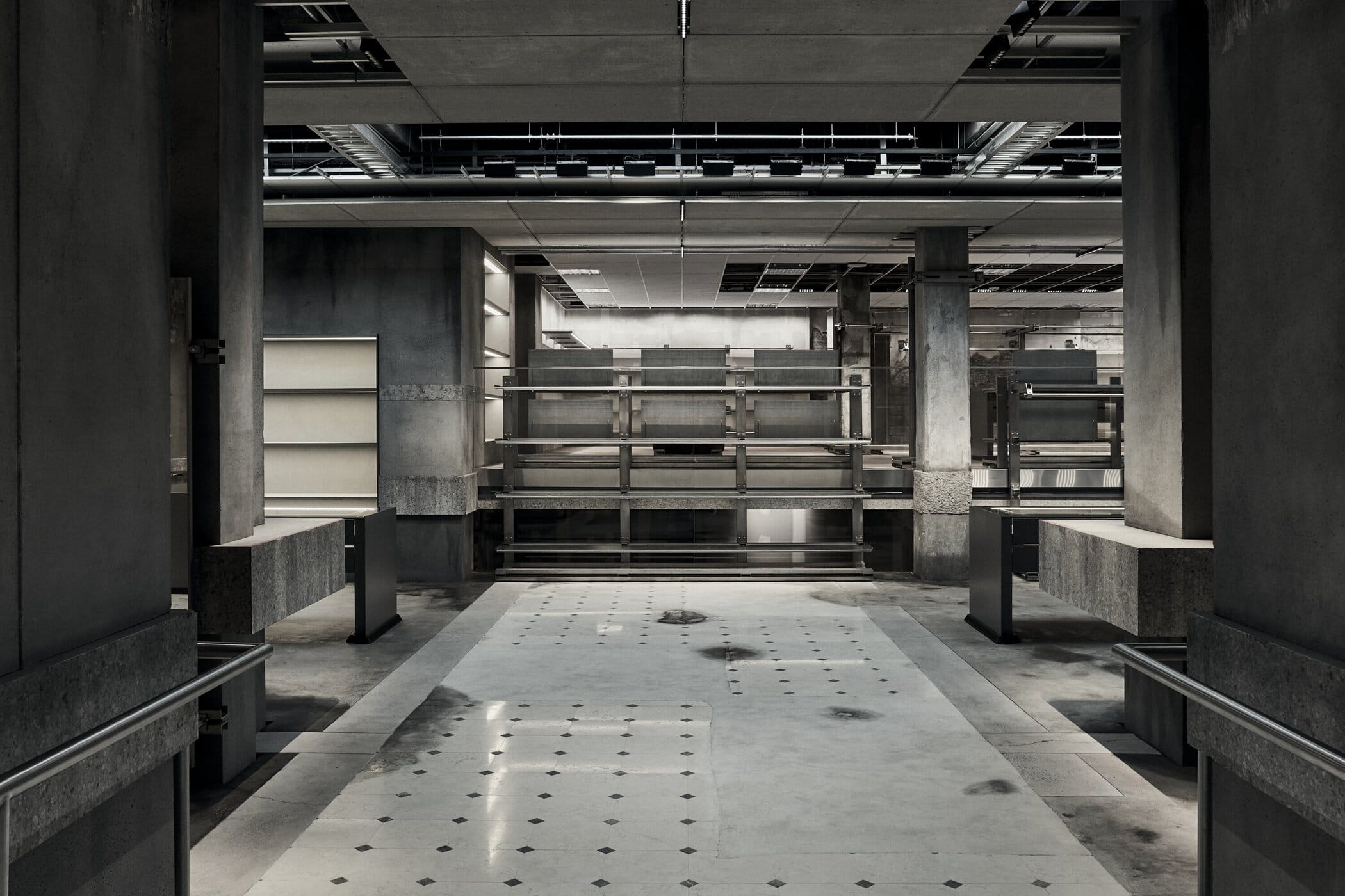Balenciaga Greene Street Flagship Store in New York — The ground floor of Balenciaga's Greene Street flagship reveals a linear passage defined by monolithic concrete support columns and a perforated concrete...