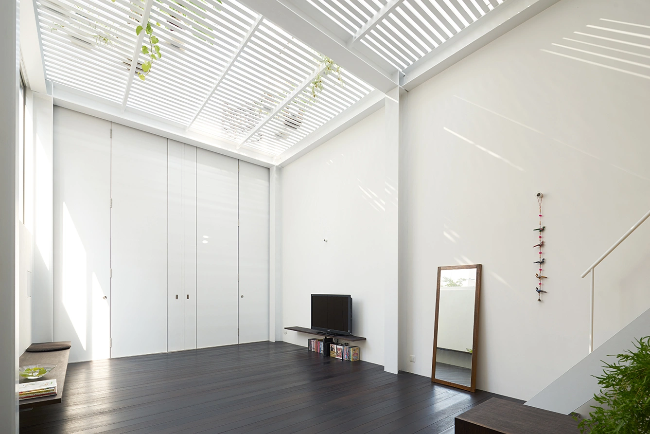 House in Kawasaki by Taichi Mitsuya & Associates — A north-facing living room anchored by floor-to-ceiling glazed storage units with white-painted vertical mullions.