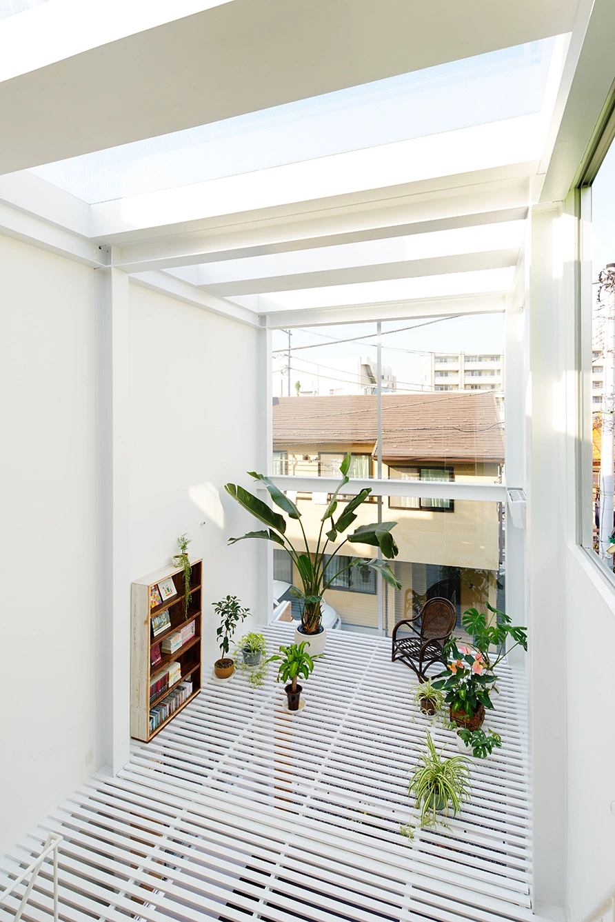 House in Kawasaki by Taichi Mitsuya & Associates — A view into the House in Kawasaki's south-facing terrace, framed by white post-and-beam structural columns supporting horizontal glazing elements.