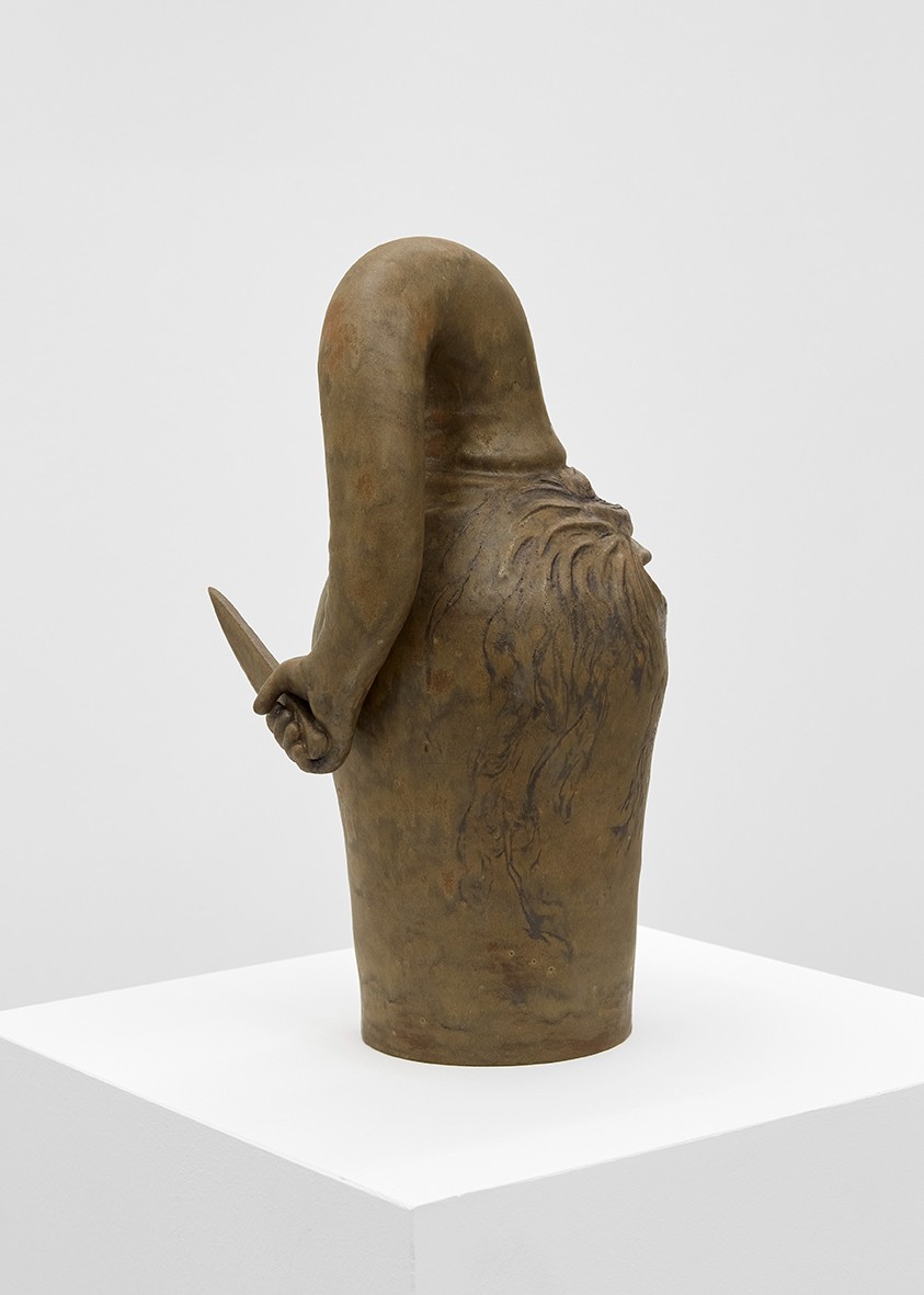 Morphogenesis at Xxijra Hii — A bronze sculptural form occupies the white pedestal at center frame, its cylindrical base tapering upward into an organic, curved silhouette.