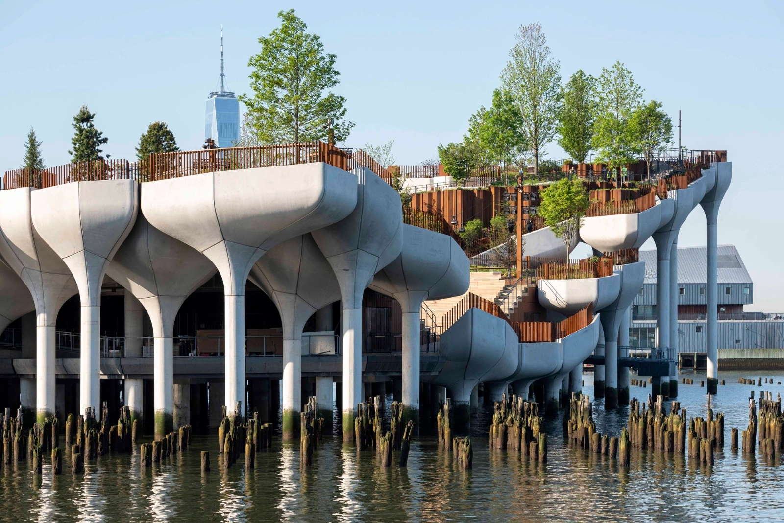 Little Island Park by Heatherwick Studio + MNLA — Timothy Schenck's photograph captures Little Island's sculptural pier infrastructure from water level, emphasizing the eight tapered concrete cylinders with...