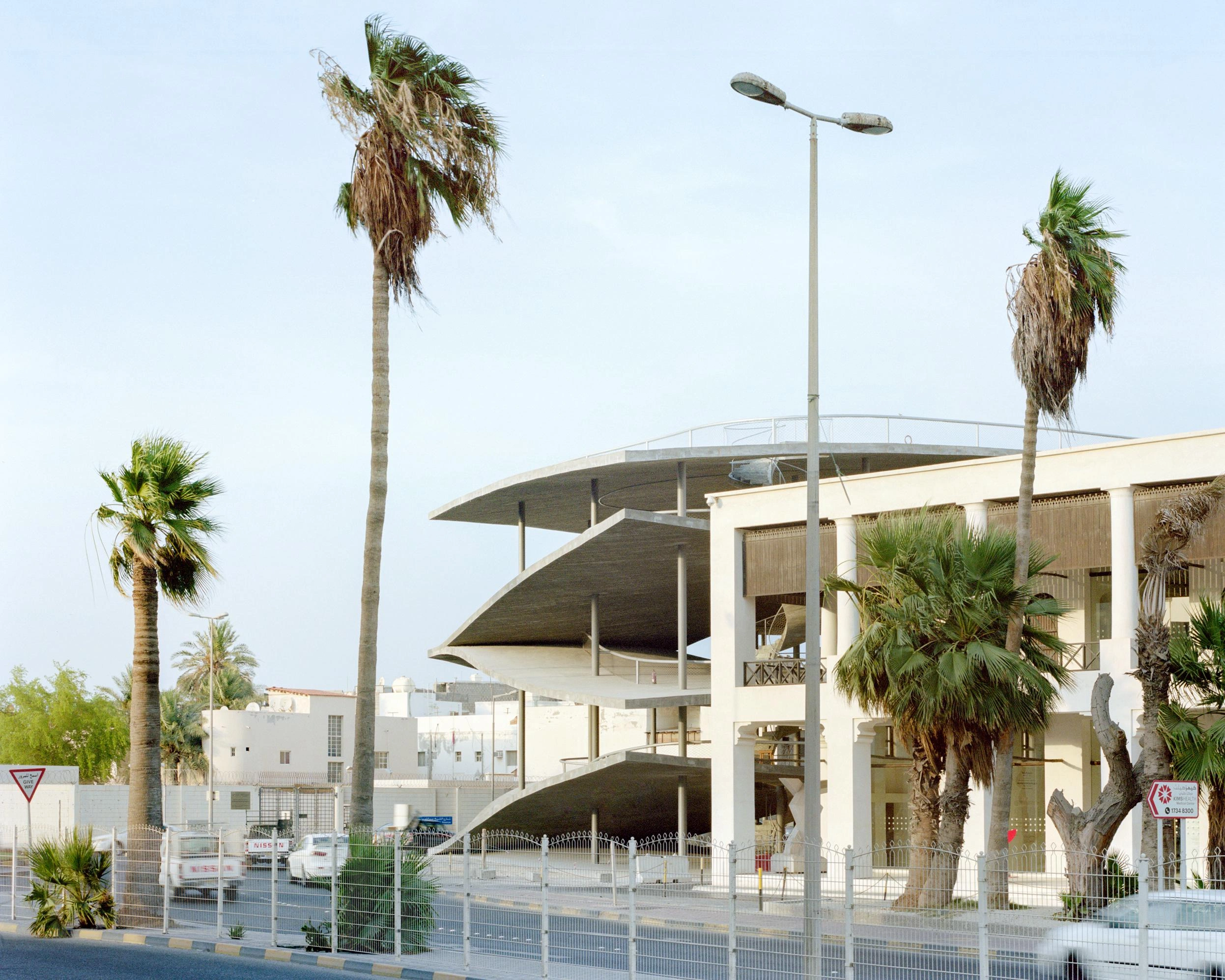 Pearling Path's Four Car Parks by Christian Kerez — Christian Kerez's car park emerges from Muharraq's street as a monolithic concrete form, its pitched roof with curved edges cantilevering dramatically over...