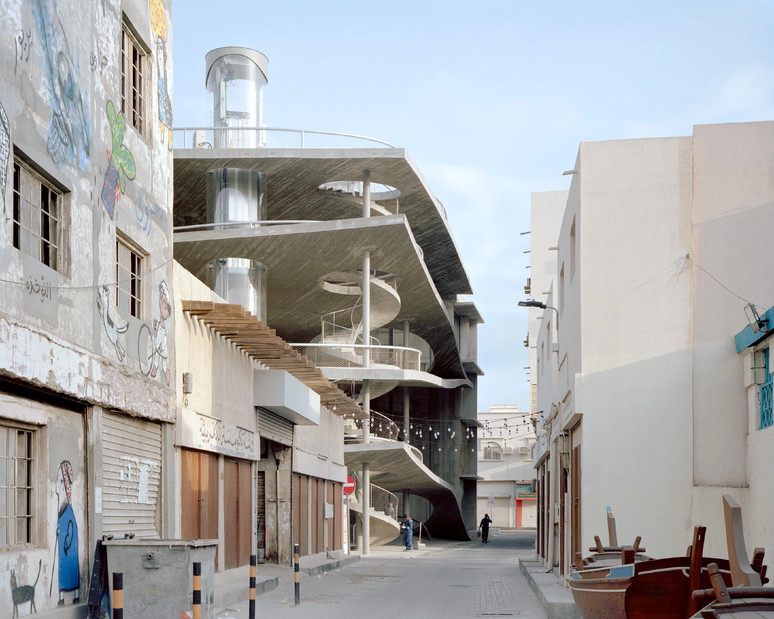 Pearling Path's Four Car Parks by Christian Kerez — Christian Kerez's car park structure cantilevers dramatically over a narrow street in Muharraq's medieval center, its pitched-roof form with curved edges...