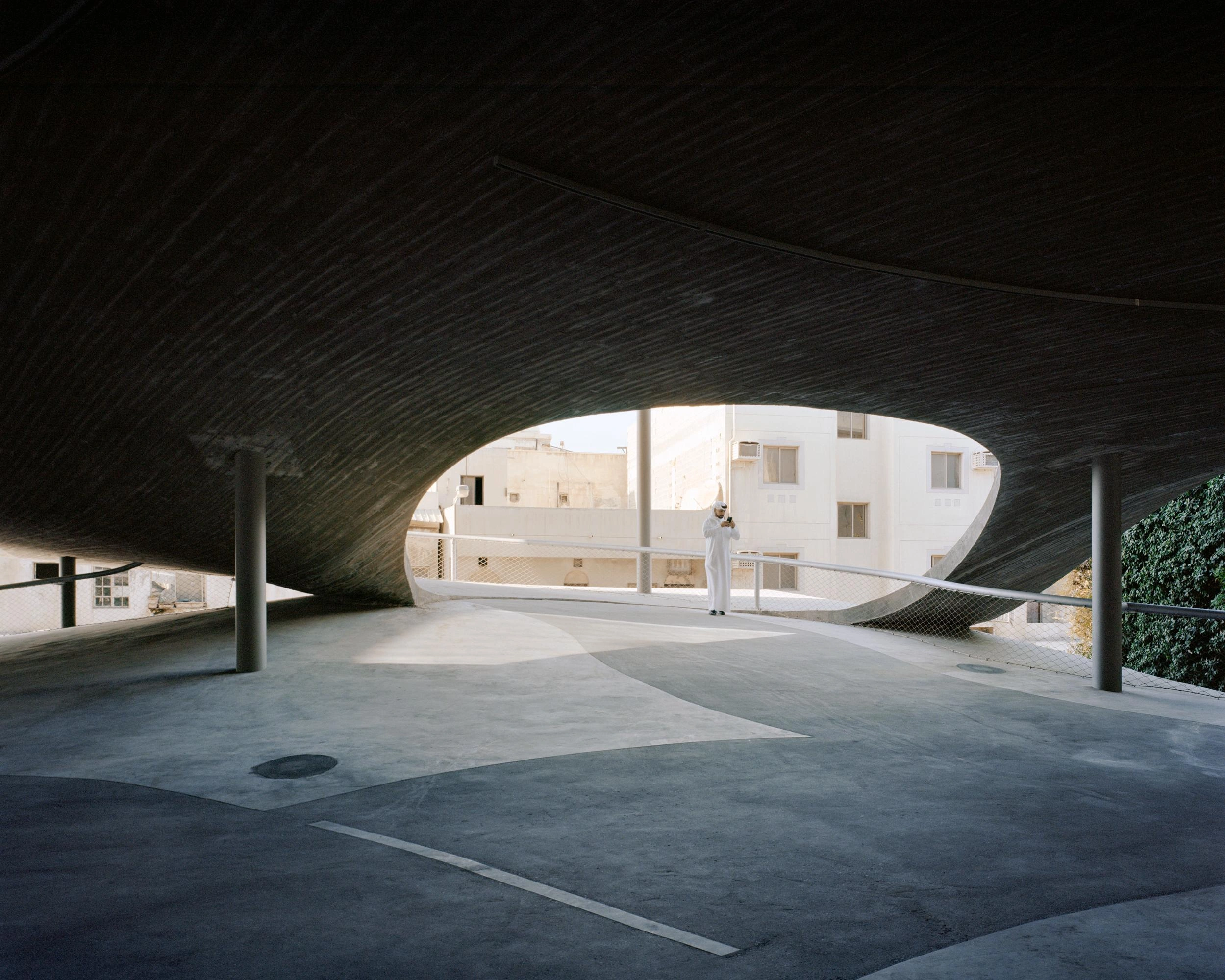 Pearling Path's Four Car Parks by Christian Kerez — Viewed from within the car park's cavernous interior, this image captures the dramatic cantilever of the pitched-roof structure extending over the street...
