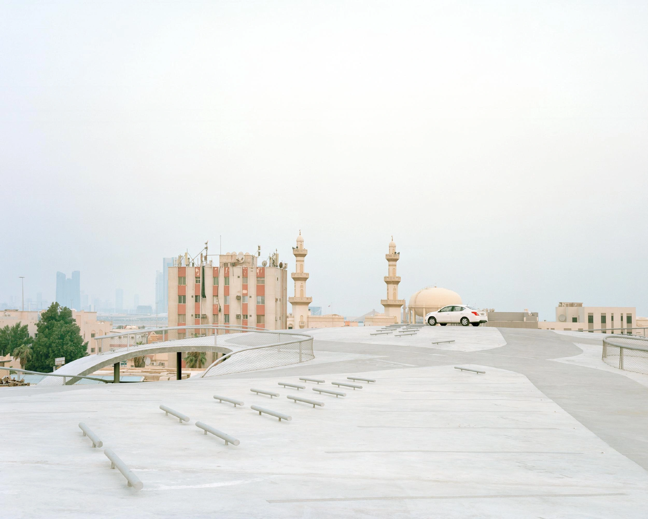 Pearling Path's Four Car Parks by Christian Kerez — A white concrete car park structure dominates the roofscape of Muharraq's medieval quarter, its sloping floor plate angled toward the street below.
