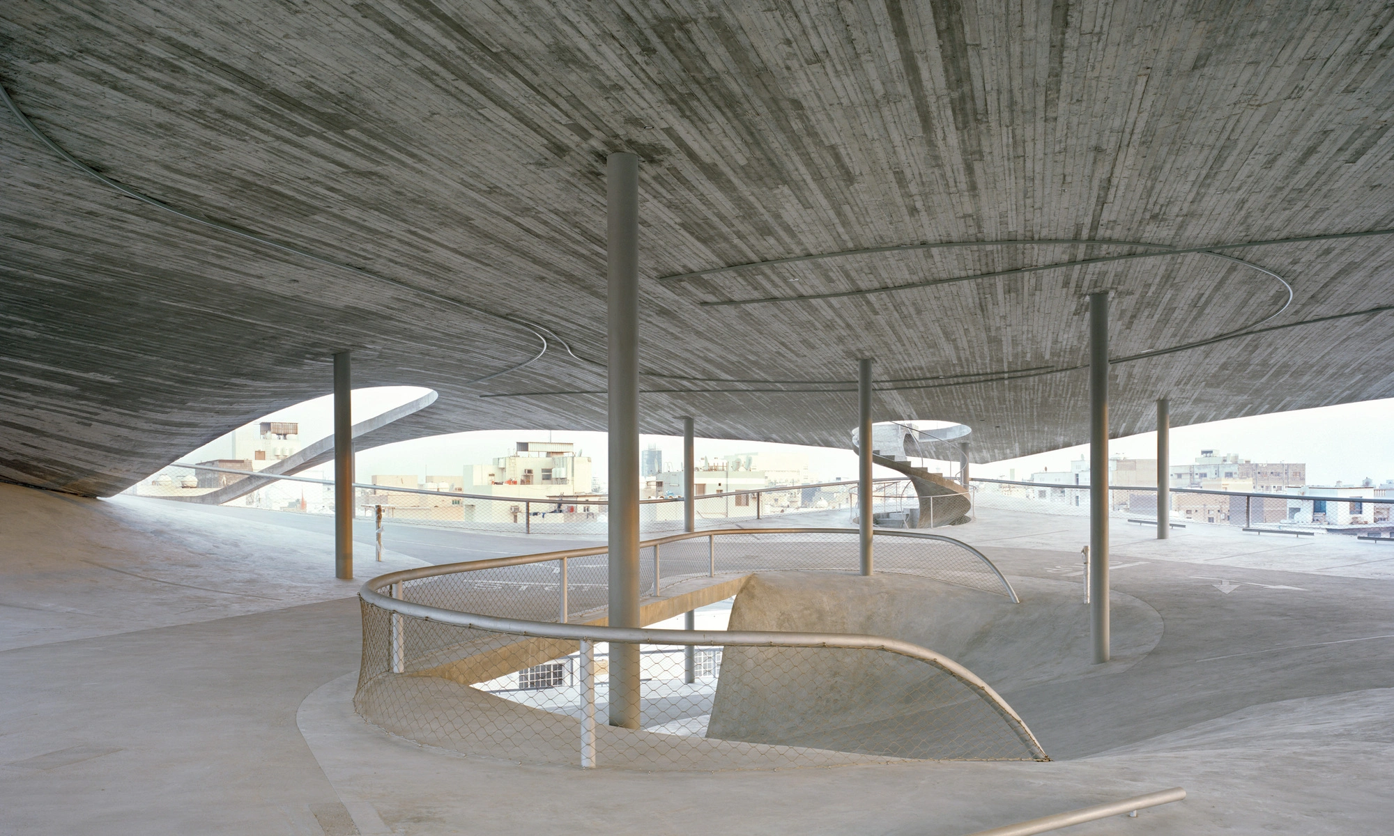 Pearling Path's Four Car Parks by Christian Kerez — A monolithic concrete car park interior reveals its structural logic through a dramatically sloped floor plate visible in cross-section.