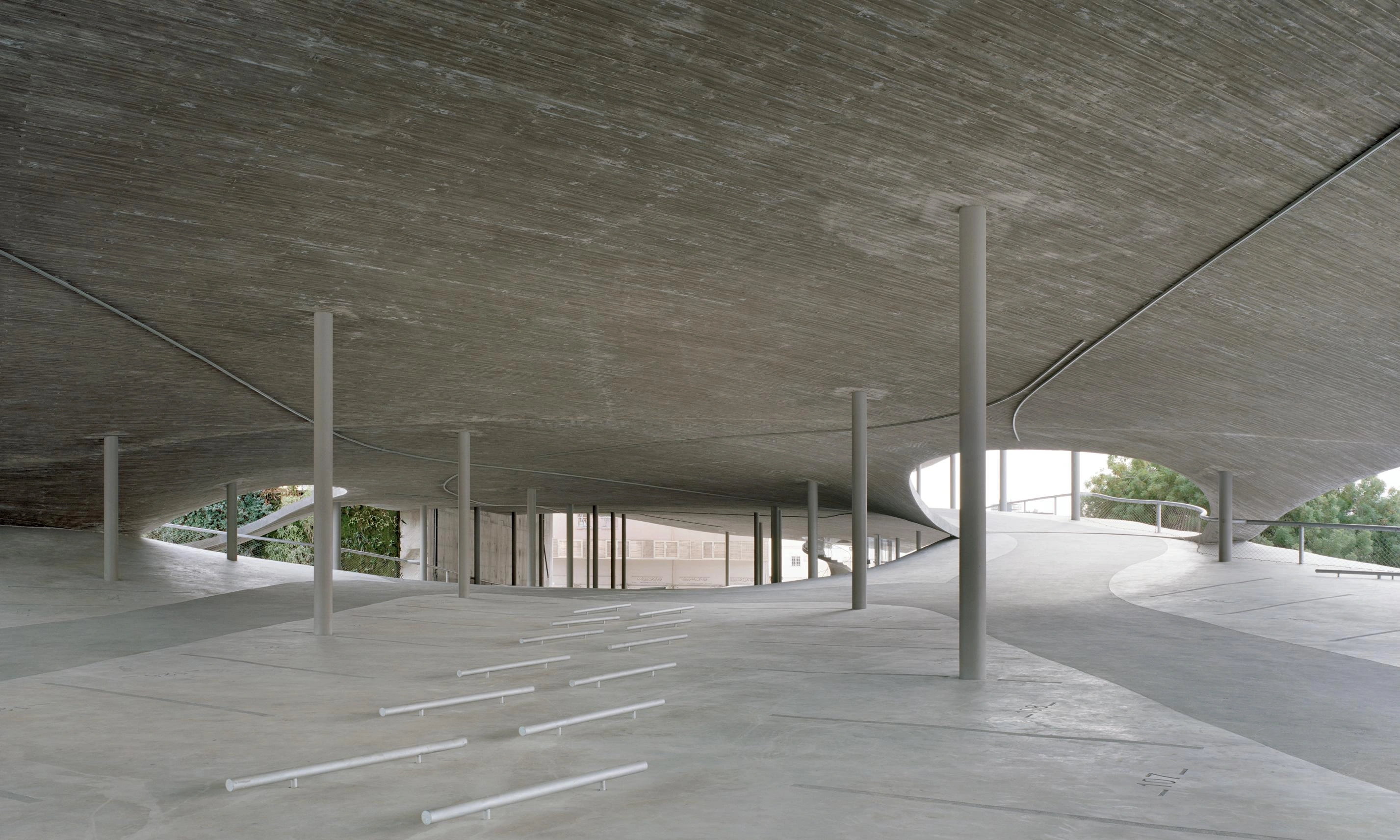Pearling Path's Four Car Parks by Christian Kerez — The ground-floor plaza of Kerez's car park unfolds as a vast concrete expanse beneath a dramatically cantilevered pitched roof.