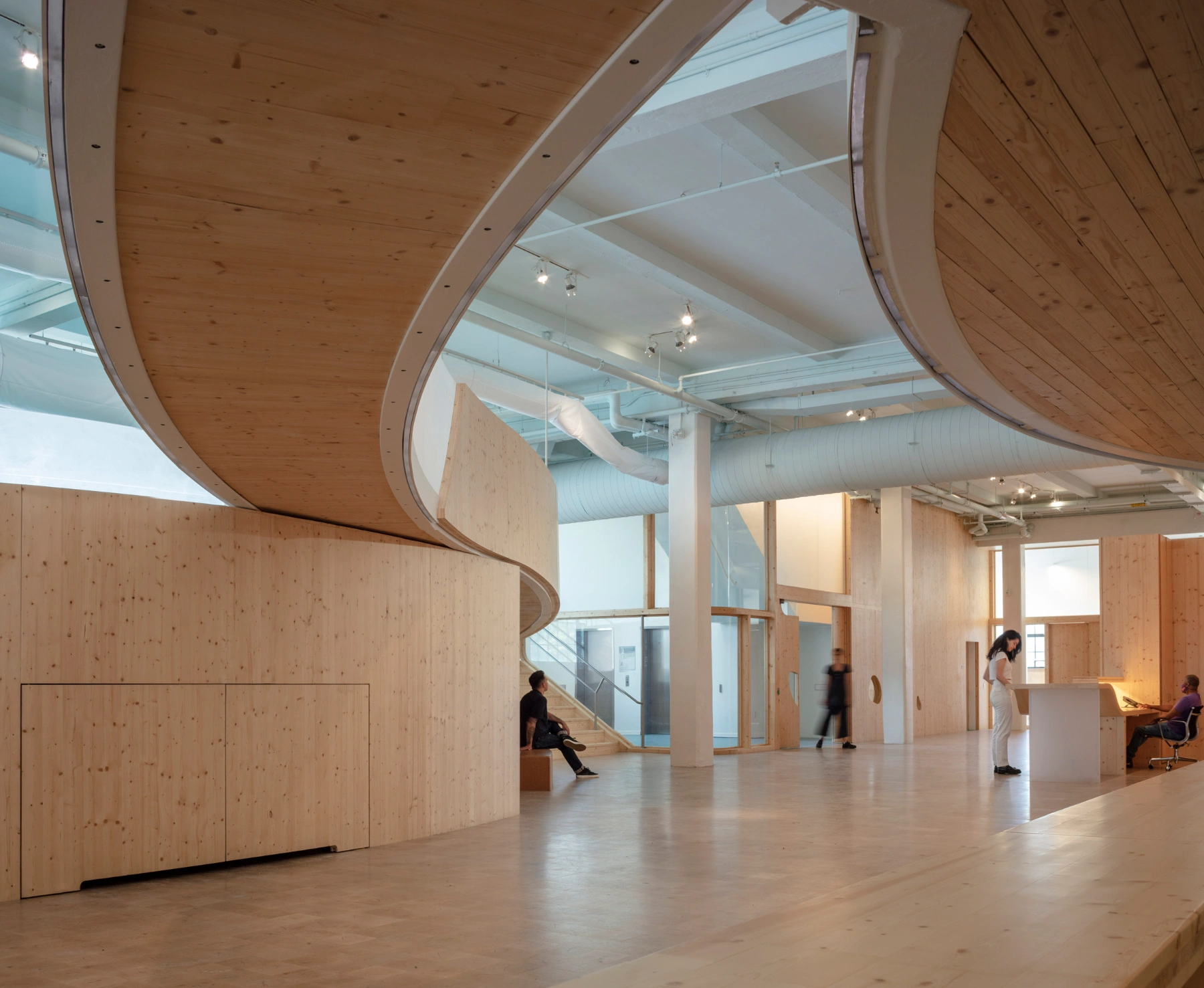 Bronx Children's Museum by O'Neill McVoy — A sculptural timber void dominates this interior volume, its concentric rings carved through light pine walls creating a spiral tunnel effect.