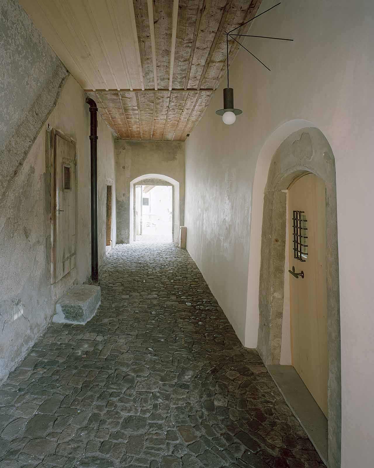 Mühle Ennenda by Atelier Lando Rossmaier — A corridor passage reveals the Mühle Ennenda's archaeological layering through material contrasts.