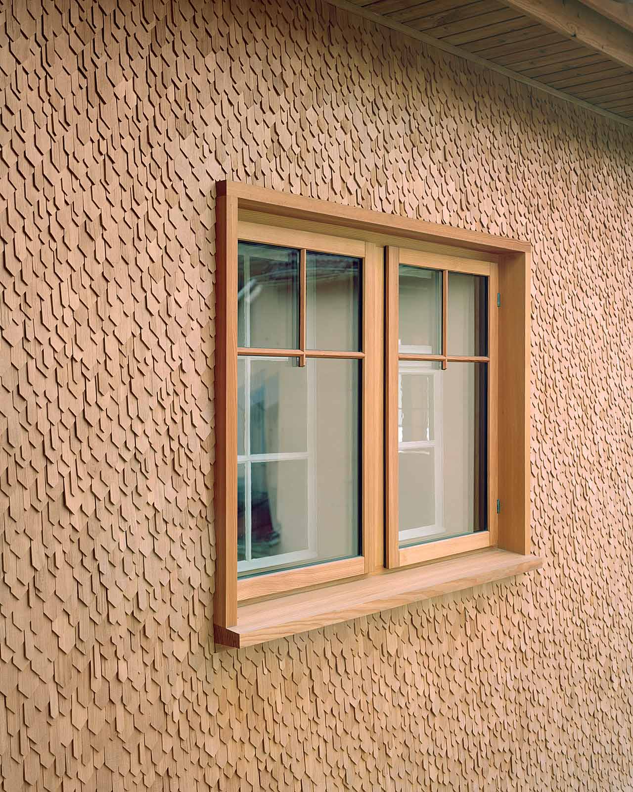 Mühle Ennenda by Atelier Lando Rossmaier — A timber-framed window opening punctures the textured brick facade, its wood surround and sill reading as a deliberate contemporary insertion against the...
