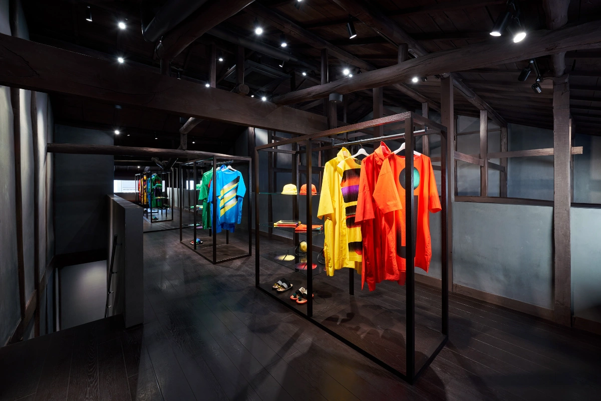 Issey Miyake Kyoto by Naoto Fukasawa Design — Interior view of display enclosures within the renovated machiya, showcasing Issey Miyake garments suspended on black metal frames.
