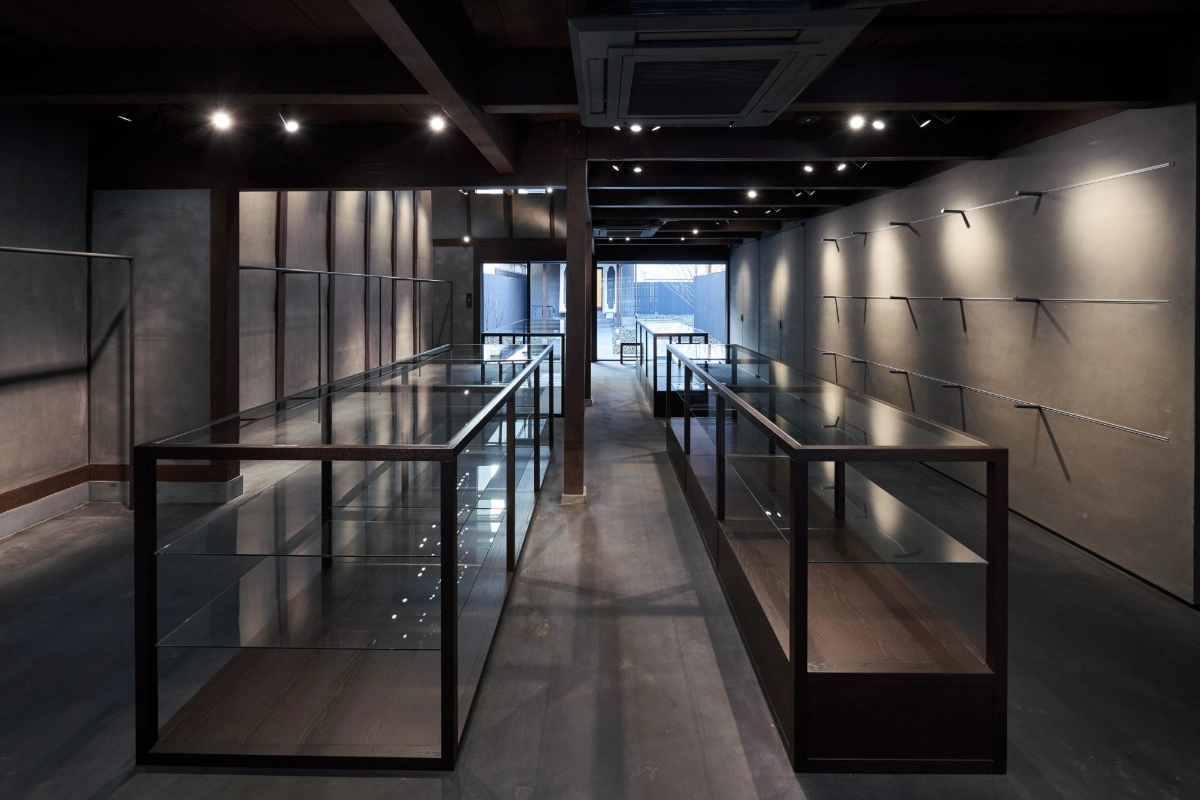 Issey Miyake Kyoto by Naoto Fukasawa Design — A corridor within the renovated machiya features a symmetrical passage flanked by two display cases with steel frames and glass panels.