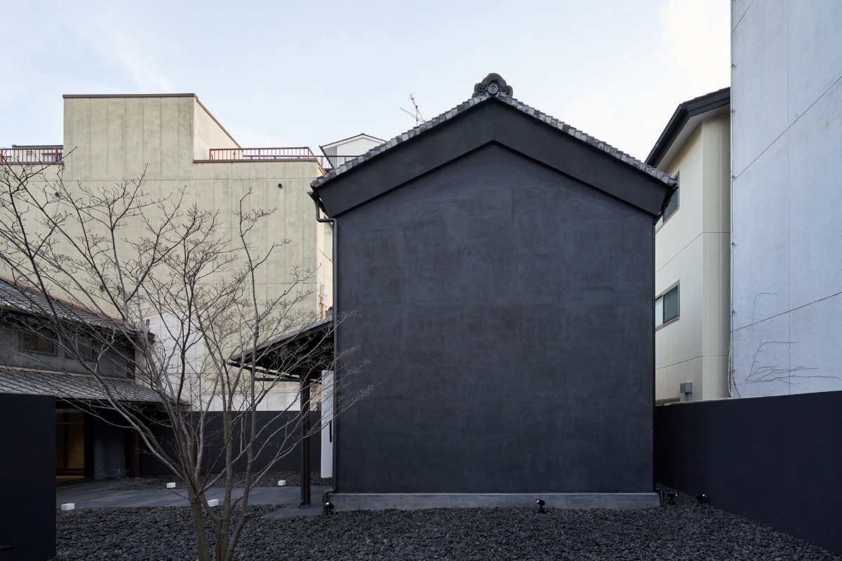 Issey Miyake Kyoto by Naoto Fukasawa Design — The renovation's monolithic black facade dominates the courtyard elevation, its rendered surface forming a stark geometric plane punctuated only by a...