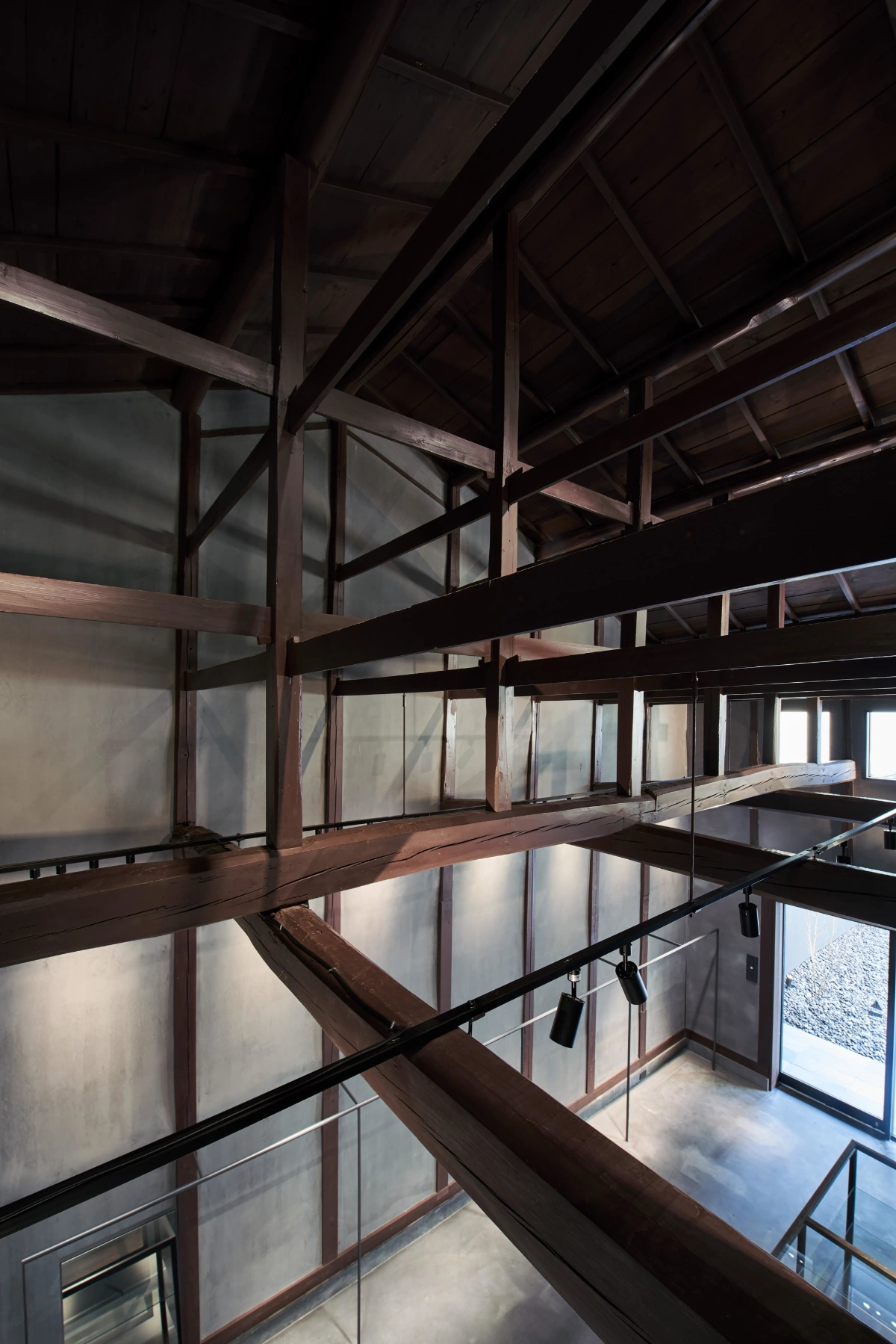 Issey Miyake Kyoto by Naoto Fukasawa Design — A multi-level interior perspective reveals the structural skeleton of the restored machiya, with dark timber post-and-beam construction creating a geometric...