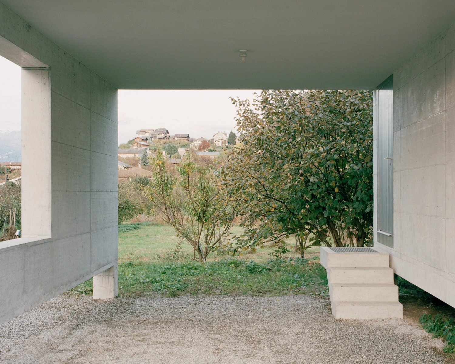 The Wandering House by Lionel Ballmer — A view through the concrete structure reveals the sheltered threshold between old and new.