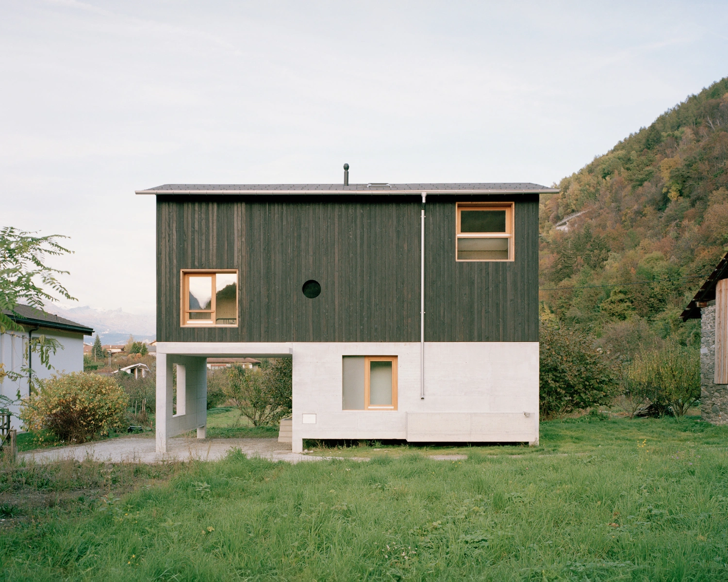The Wandering House by Lionel Ballmer — A modest residential structure positioned in alpine terrain, the house employs a two-part material strategy: the upper volume wraps in vertical timber...