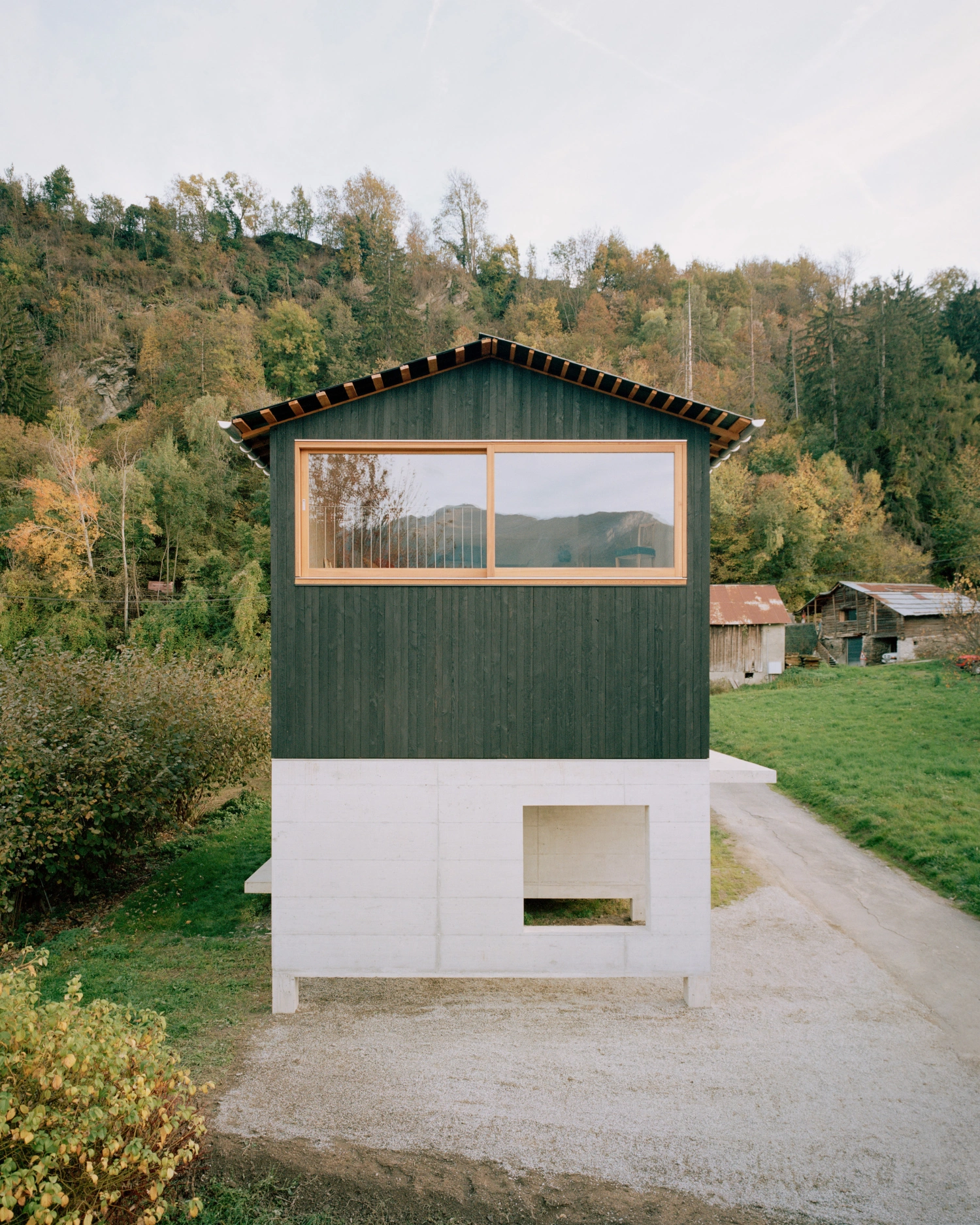The Wandering House by Lionel Ballmer — A compact dwelling raised on a white concrete plinth sits within a rural Alpine valley.