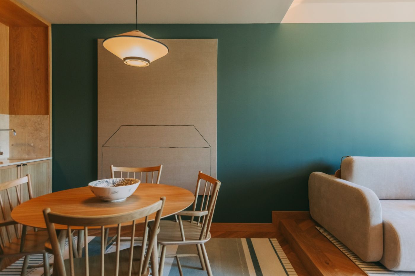 Torel Quinta da Vacaria in Douro Valley by Studio Astolfi and architect Luís Miguel Oliveira — A dining room anchored by a circular timber table with turned wooden chairs, centered beneath a sculptural pendant light suspended from a neutral ceiling.