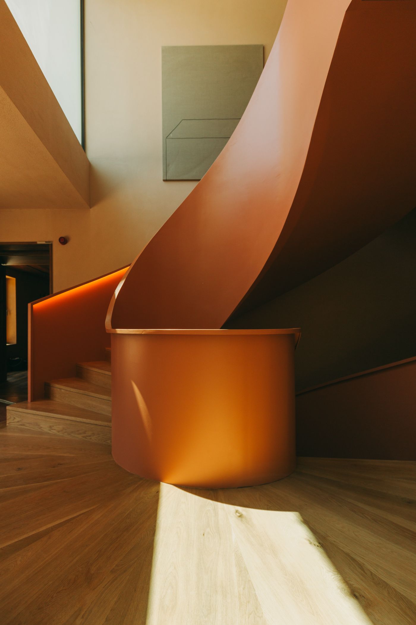 Torel Quinta da Vacaria in Douro Valley by Studio Astolfi and architect Luís Miguel Oliveira — A sculptural cylindrical form in rust-toned metal anchors the foreground of this interior passage, its curved surface catching warm pendant light.
