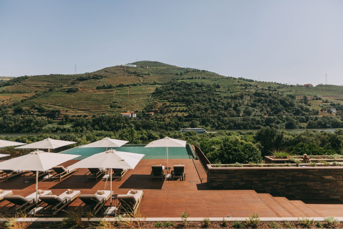 Torel Quinta da Vacaria in Douro Valley by Studio Astolfi and architect Luís Miguel Oliveira — The pool deck at Torel Quinta da Vacaria frames the Douro Valley landscape through a composition of horizontal planes and shade structures.