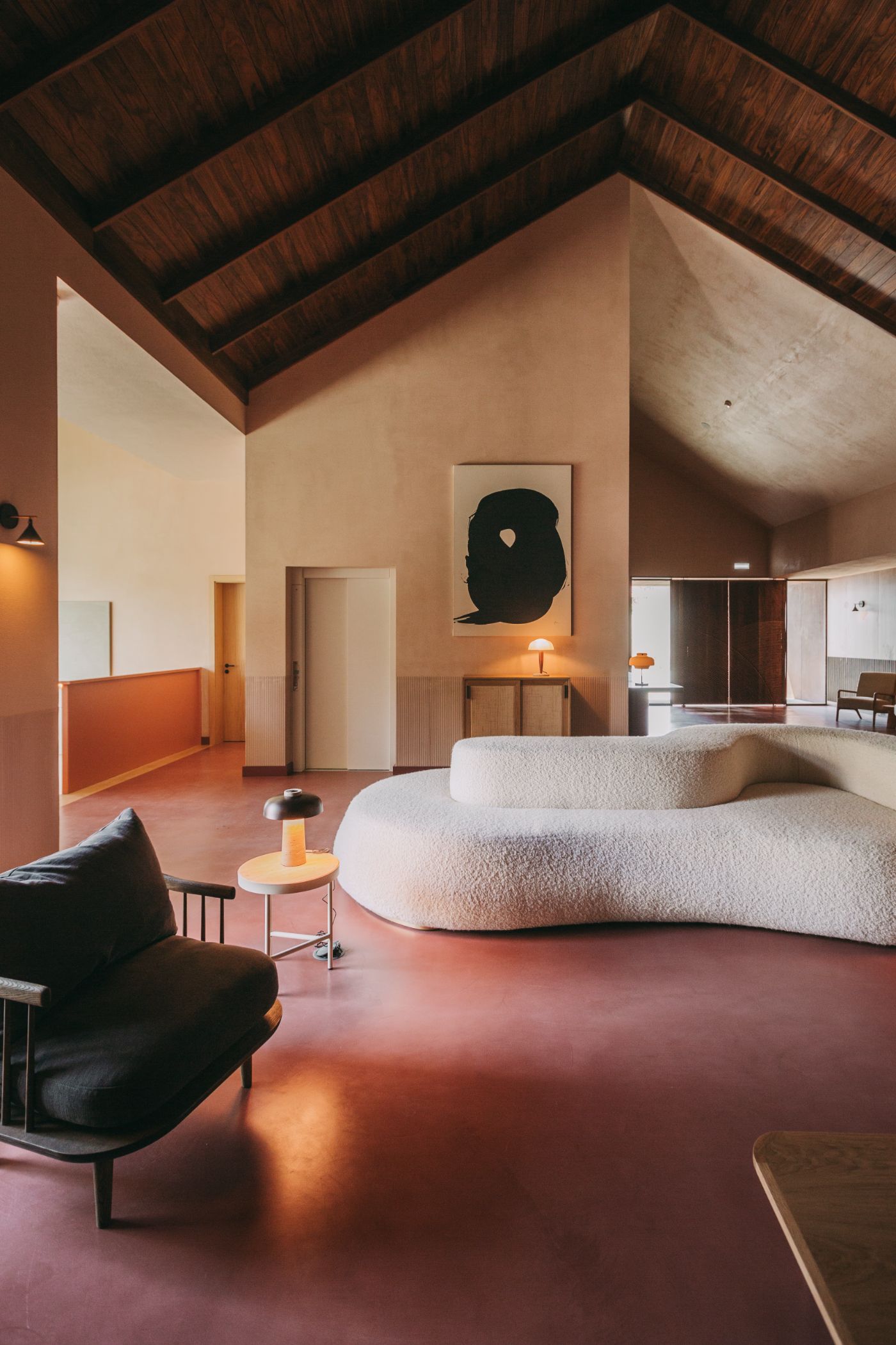 Torel Quinta da Vacaria in Douro Valley by Studio Astolfi and architect Luís Miguel Oliveira — A bedroom interior dominated by a sculptural cream-colored upholstered seating element with organic curved forms positioned centrally on polished terracotta...