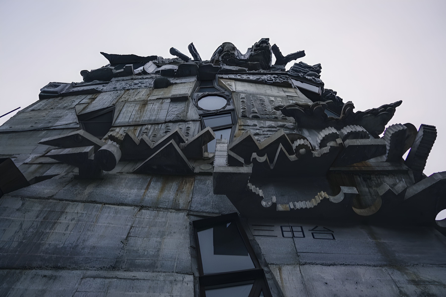Arimaston Building by Keisuke Oka — Keisuke Oka's Arimaston Building photographed from a low angle that emphasizes its crowning sculptural mass—a dense aggregation of protruding concrete...