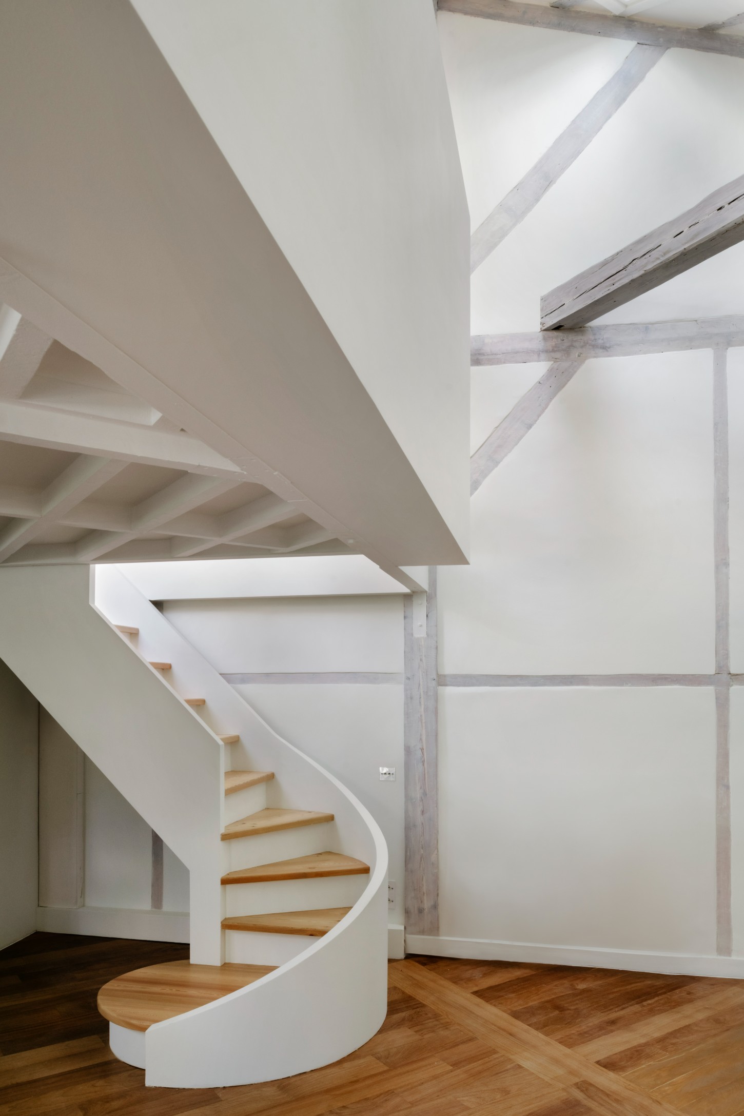 Atelier 22 by Atelier Mula Scala + Atelier Mas by Atelier Mura Scala and Atelier Mas — A sculptural spiral staircase dominates the double-height interior, its curved white plaster form anchoring the rehabilitated Montmartre studio.
