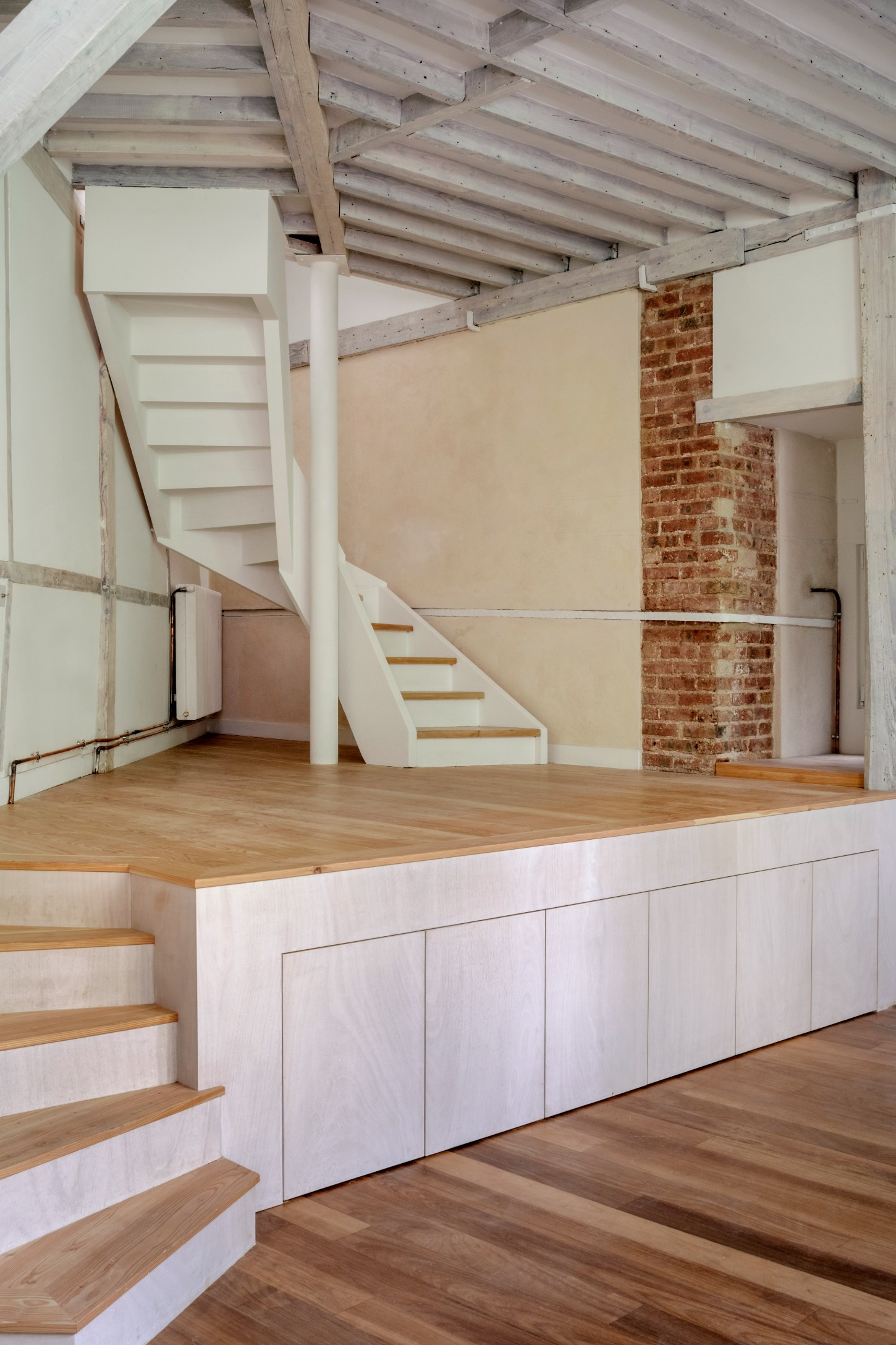Atelier 22 by Atelier Mula Scala + Atelier Mas by Atelier Mura Scala and Atelier Mas — A double-height studio space reveals its original structural logic through exposed timber beams with pale finish overhead.