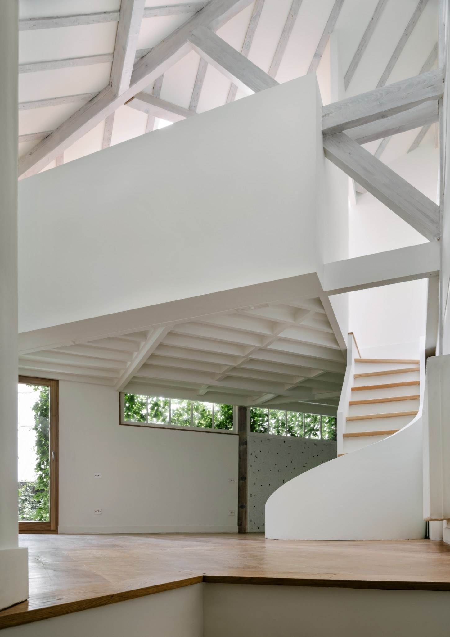 Atelier 22 by Atelier Mula Scala + Atelier Mas by Atelier Mura Scala and Atelier Mas — A double-height interior reveals the studio's original post-and-beam timber structure with pale-finished overhead beams creating a geometric rhythm.