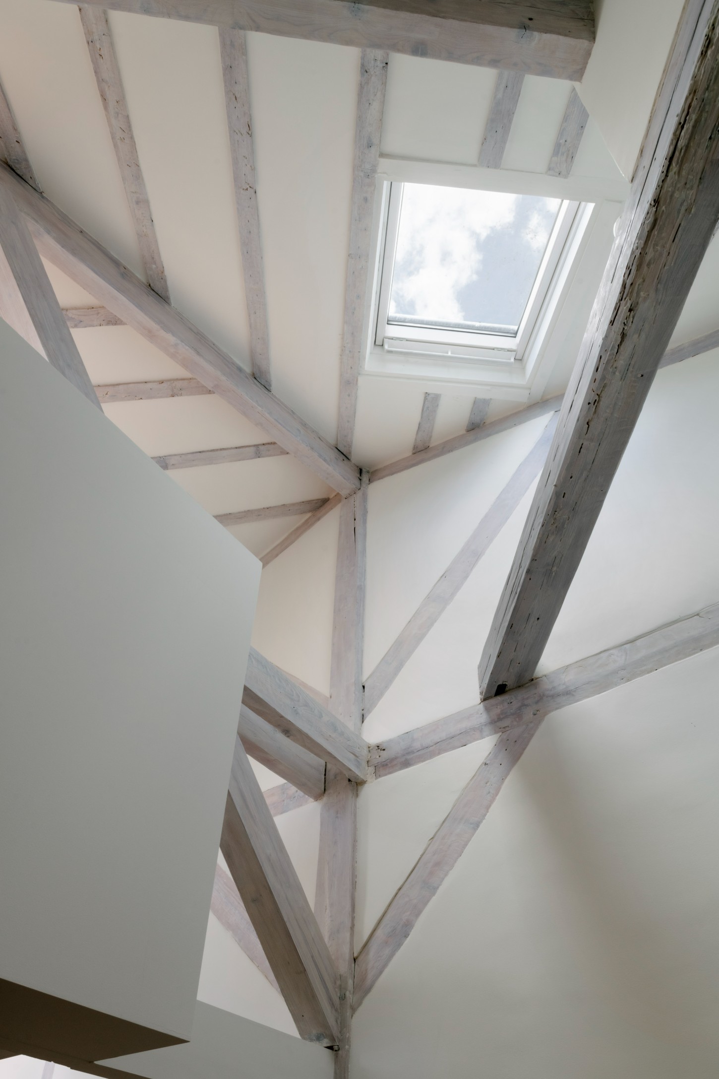 Atelier 22 by Atelier Mula Scala + Atelier Mas by Atelier Mura Scala and Atelier Mas — Overhead view of a timber-framed sculptural staircase element with curved white plaster surfaces dominating the right side of the composition.