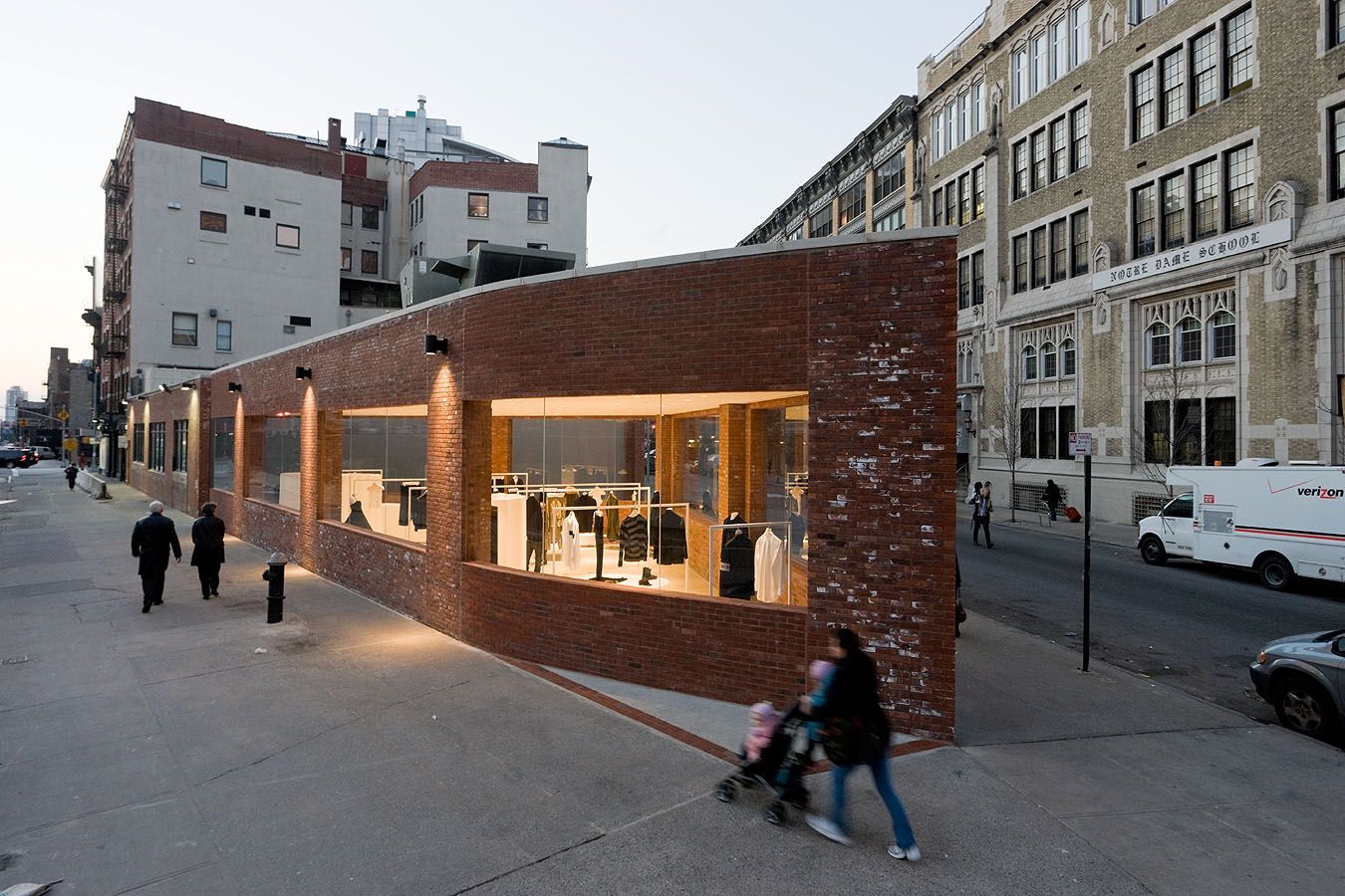 Yohji Yamamoto NYC Store by Junya Ishigami — Golden-hour light washes across the weathered brick facade of Ishigami's Yohji Yamamoto store, illuminating the curved wall that tapers toward the...