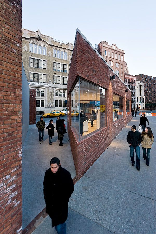 Yohji Yamamoto NYC Store by Junya Ishigami — Pedestrians navigate the carved passage bisecting Ishigami's wedge-shaped structure, their movement framing the project's spatial strategy.