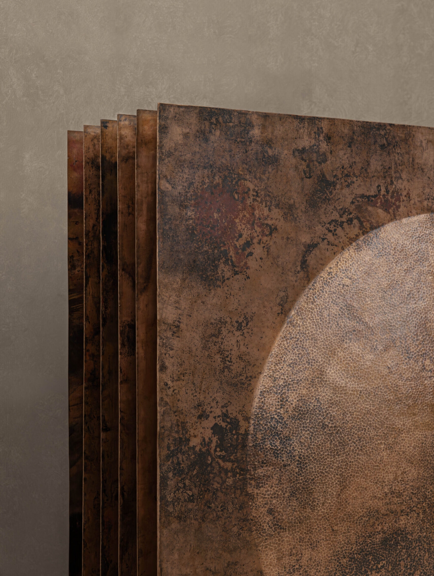 New Works by Manu Bañó — A stacked series of oxidized copper panels fan outward in graduated depth, their surfaces displaying the material's dual nature: polished convex and concave...