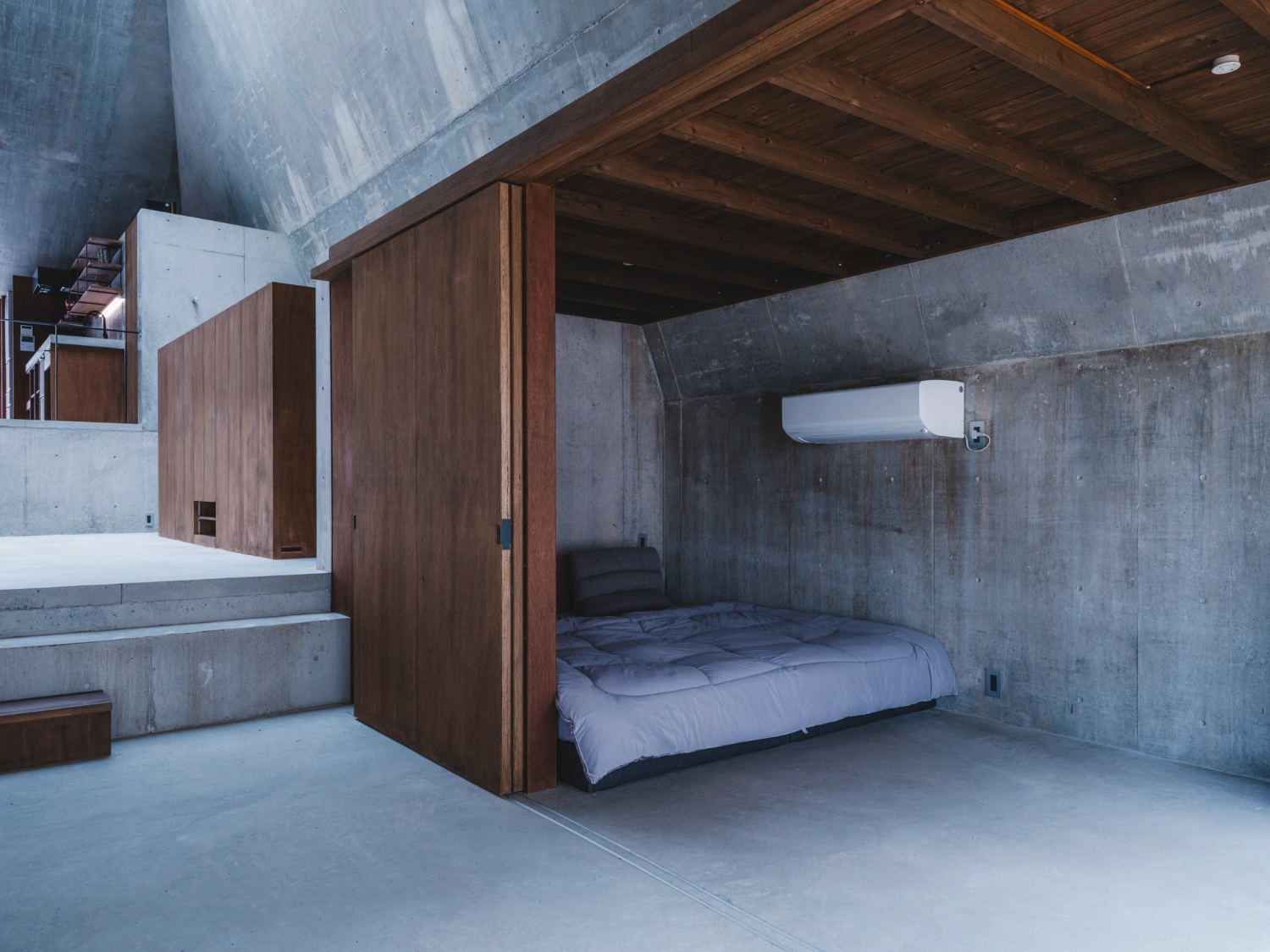 Pyramid Hut by IGArchitects — Interior view of Pyramid Hut reveals the material dialogue between monolithic concrete and timber interventions.