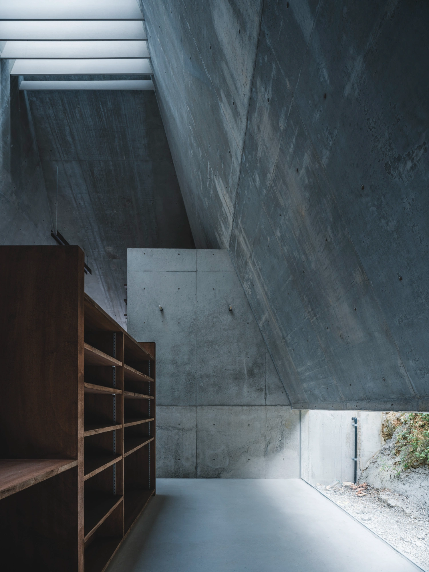 Pyramid Hut by IGArchitects — A concrete interior passage photographed from an elevated vantage point, revealing the building's structural logic through layered concrete planes.