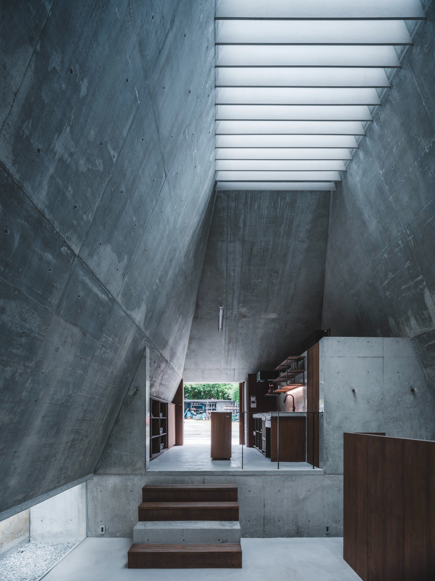 Pyramid Hut by IGArchitects — A linear perspective down a monolithic concrete corridor reveals the residence's interior spatial organization.